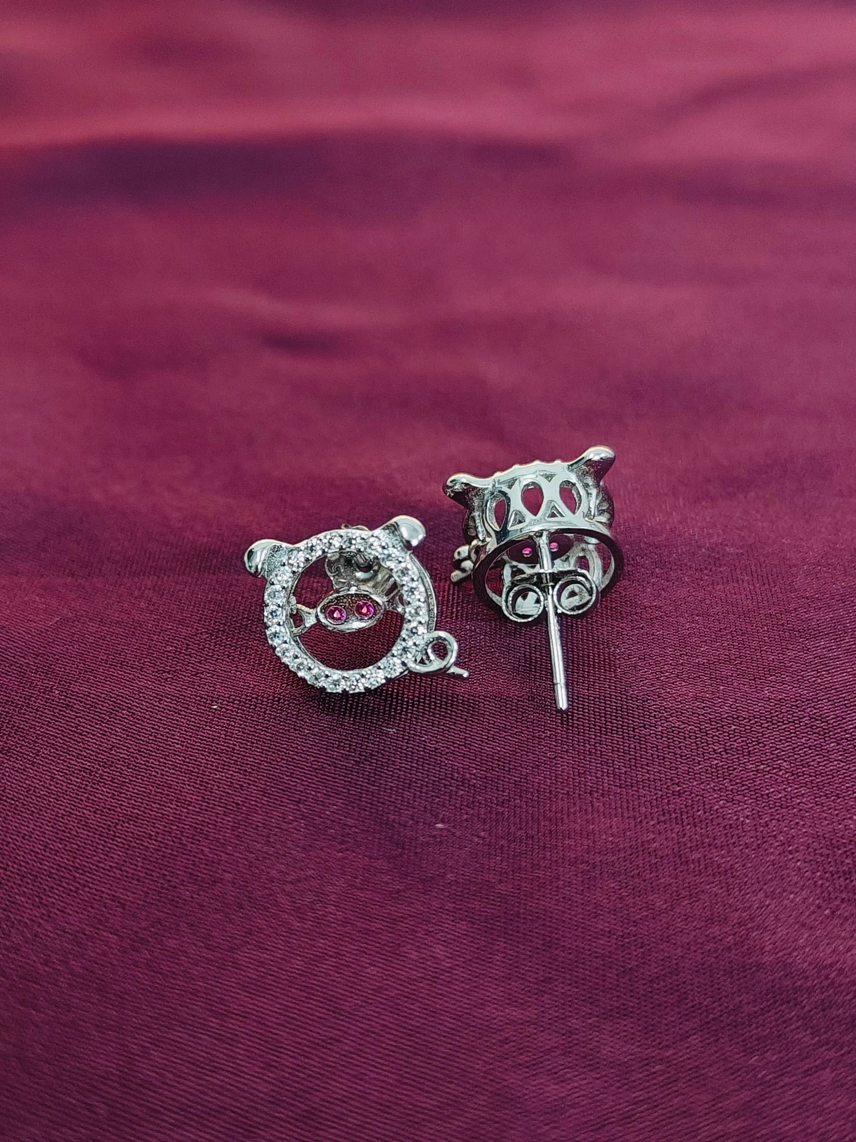 Pair of silver earrings with red gemstones on a purple fabric background