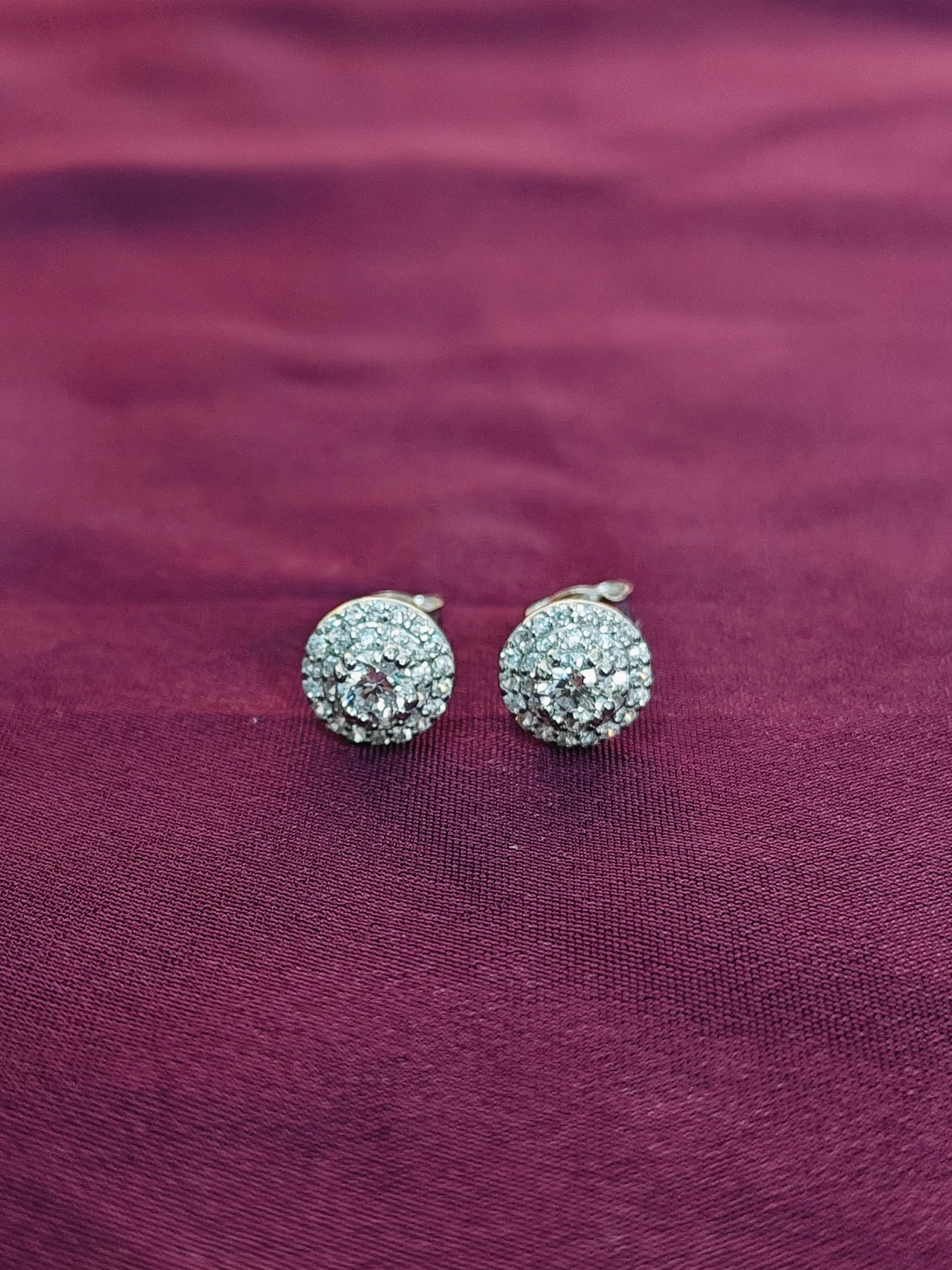 Pair of silver earrings with clear stones on a purple fabric background