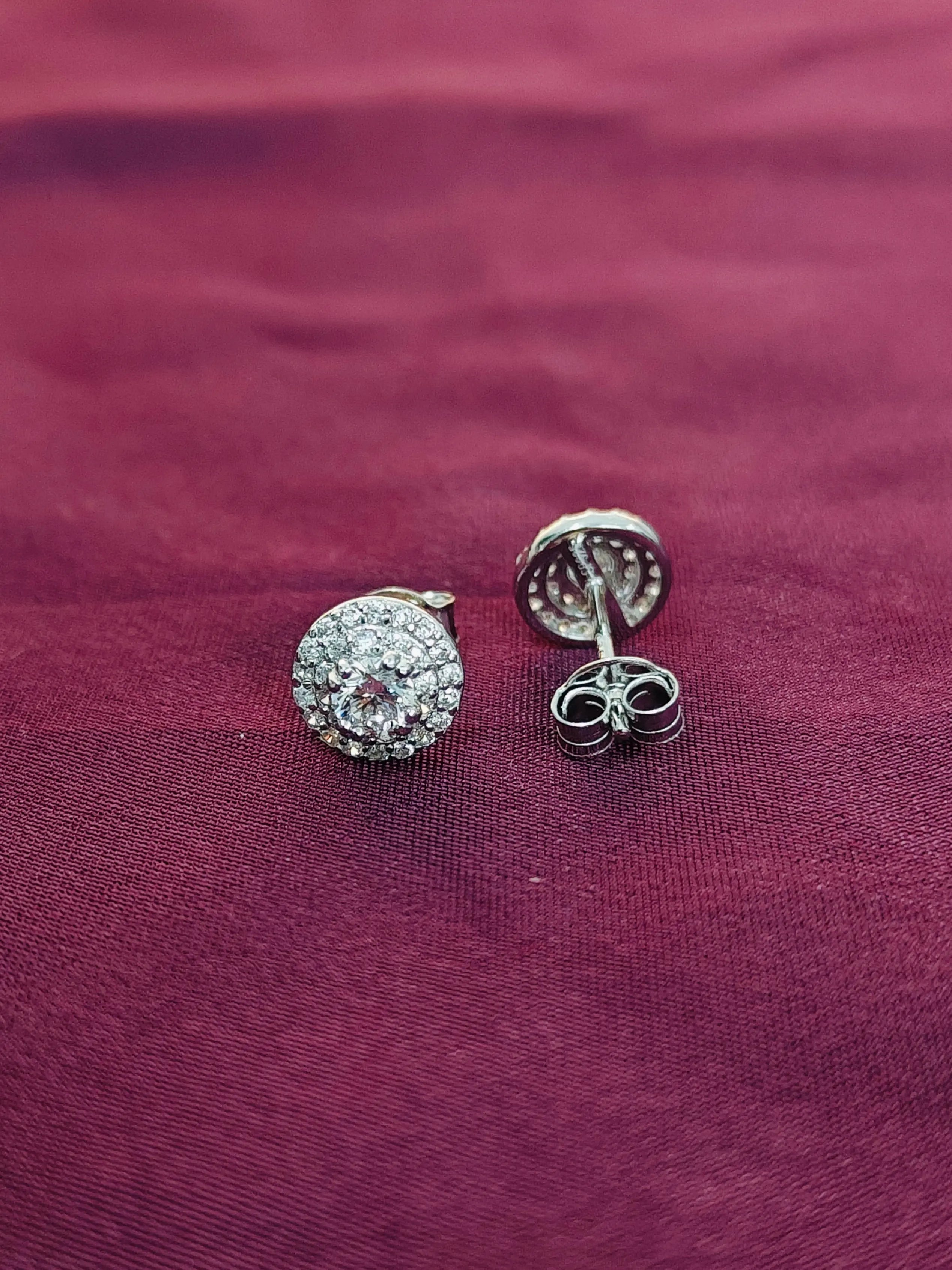 Pair of silver earrings with clear stones on a purple fabric background