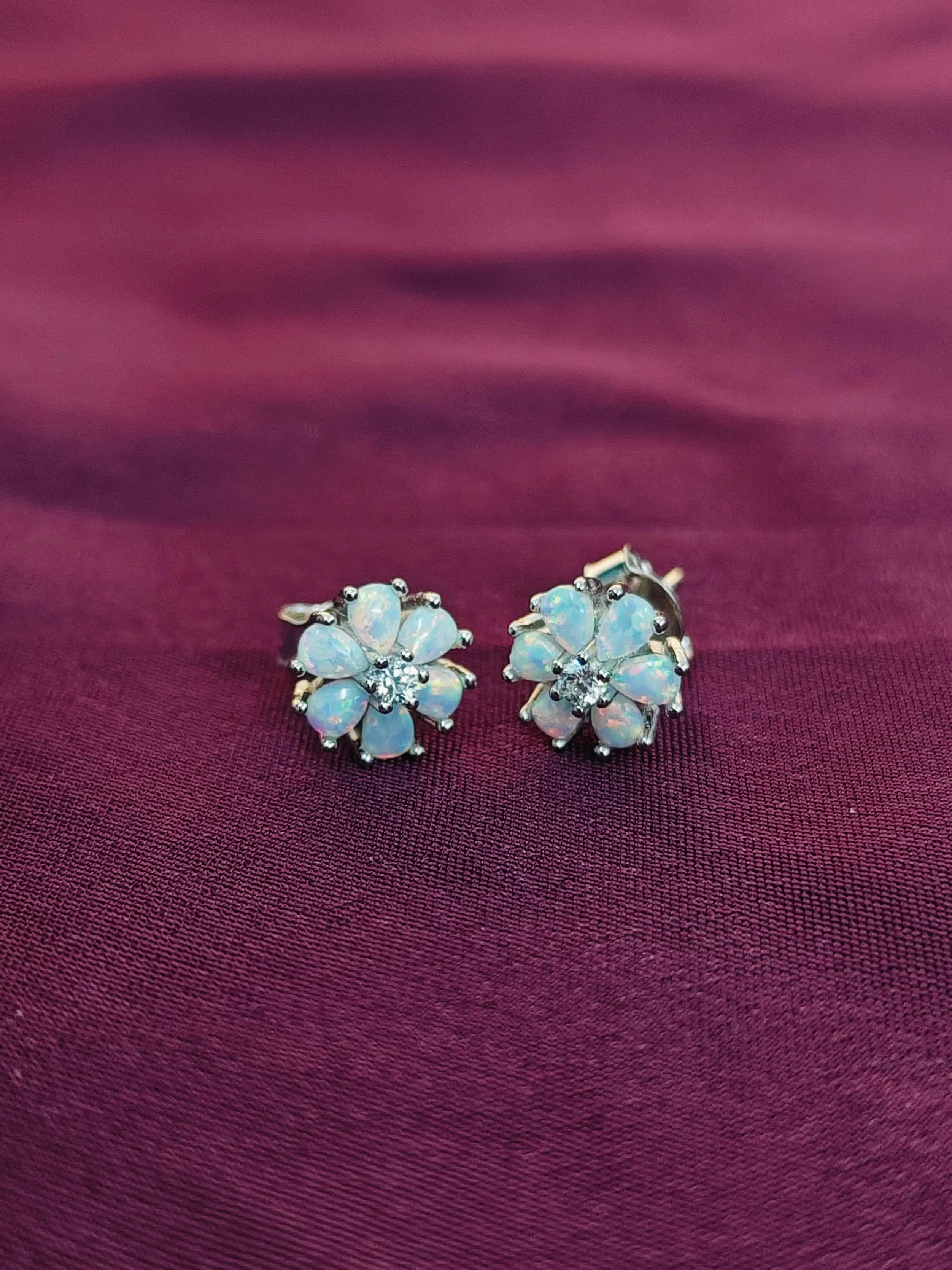 Pair of floral earrings with gemstones on a purple fabric background