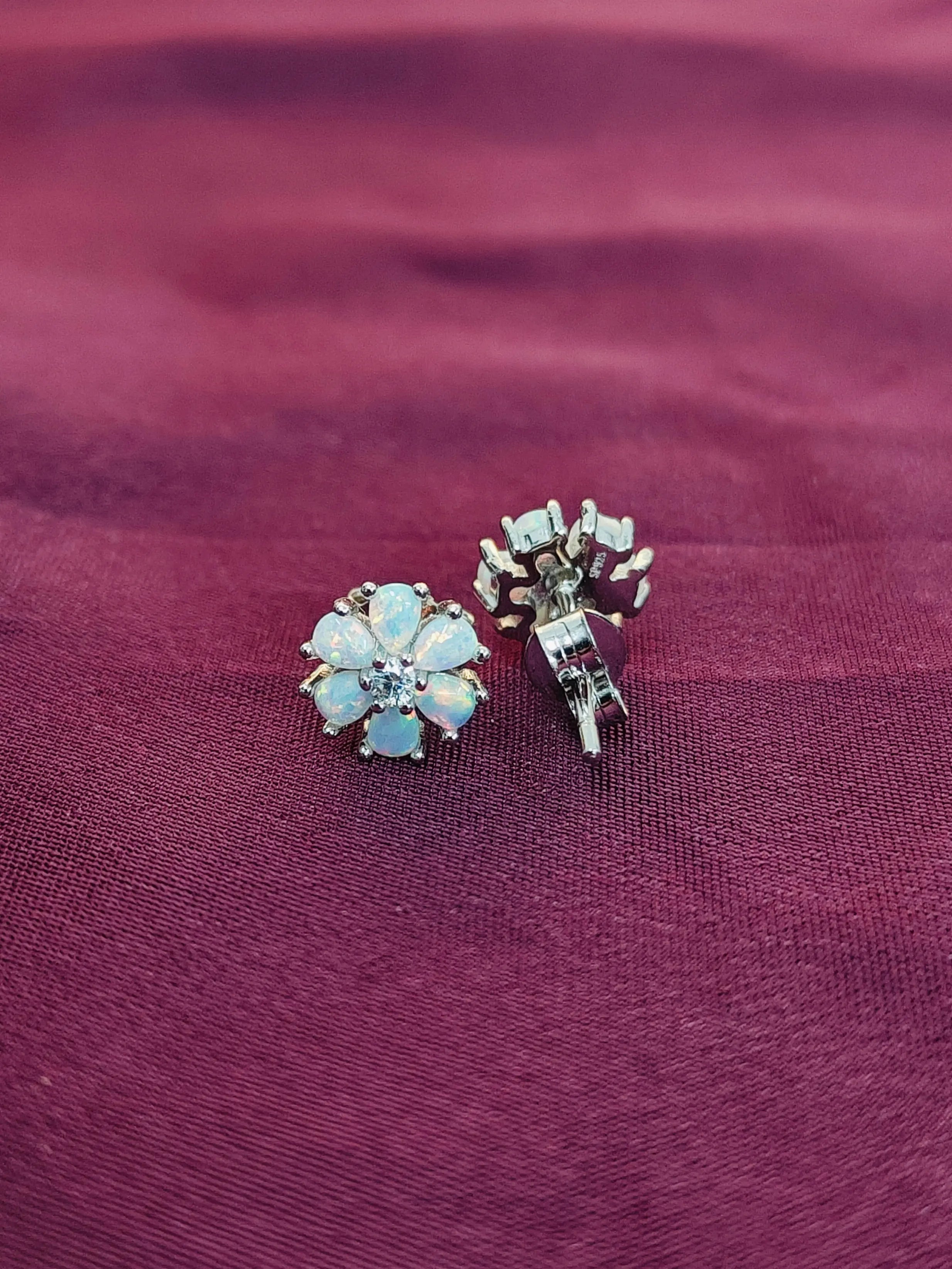 Pair of floral earrings on a maroon fabric background