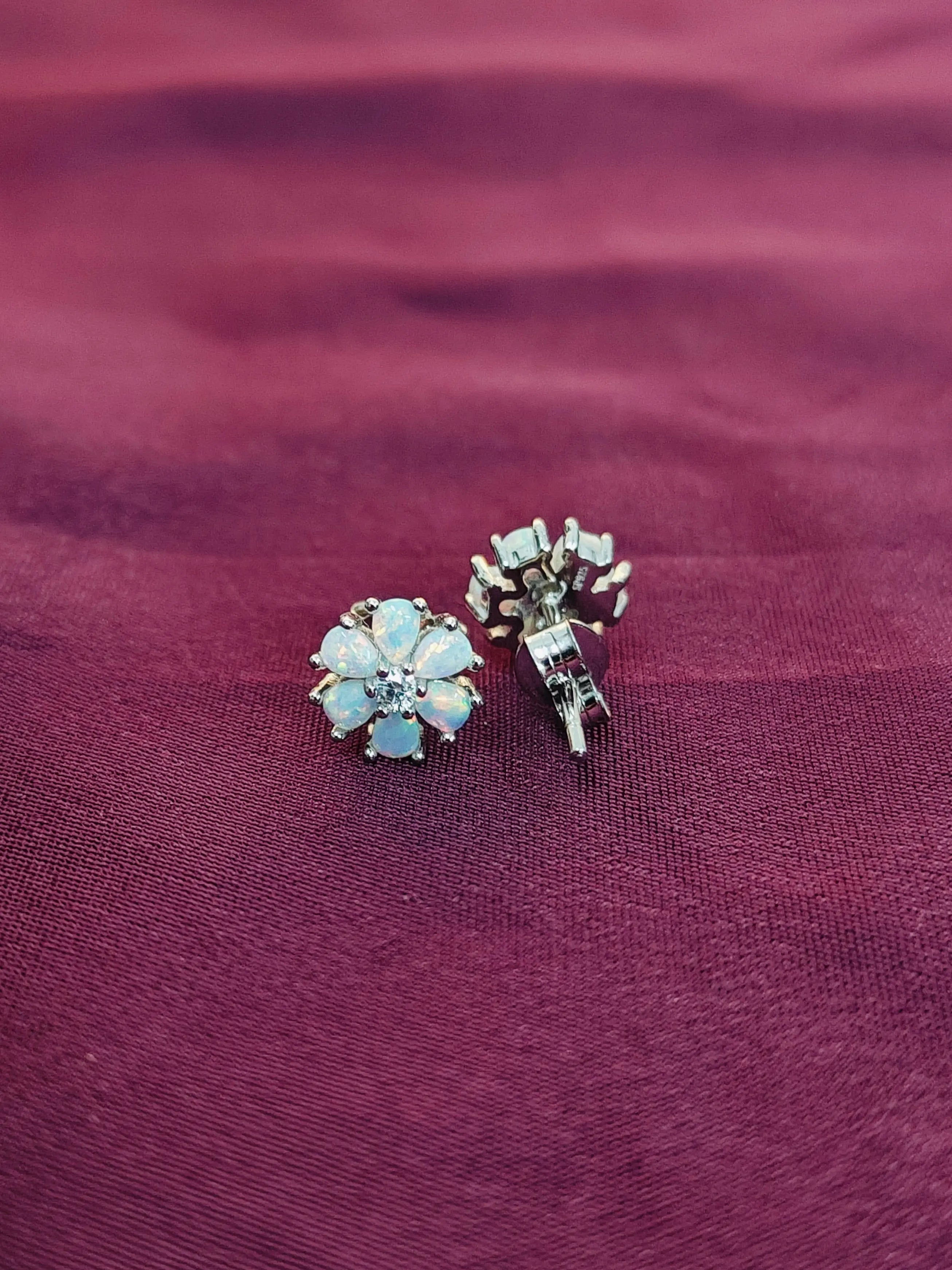 Two pairs of earrings on a maroon fabric background