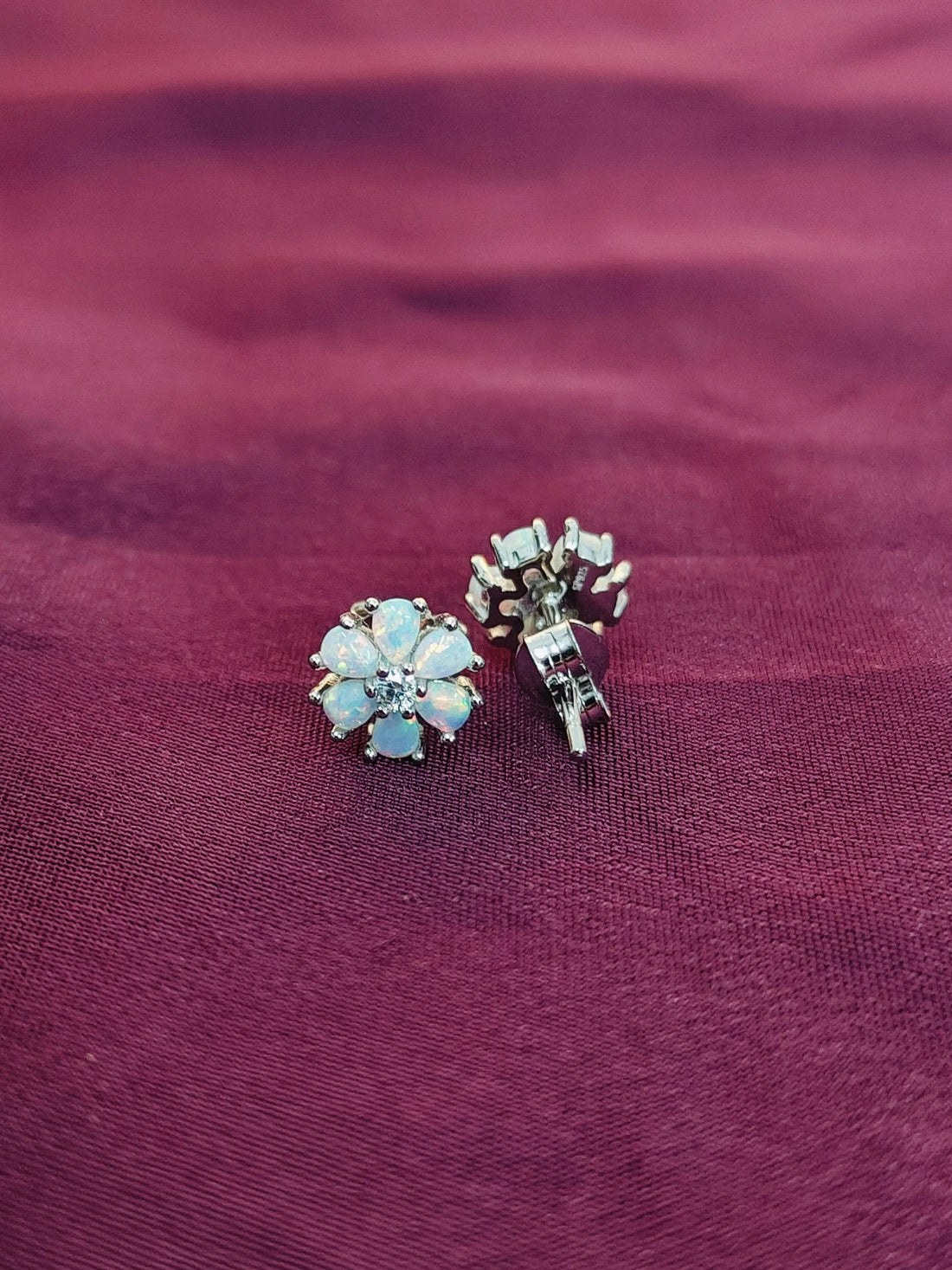 Two pairs of earrings on a maroon fabric background