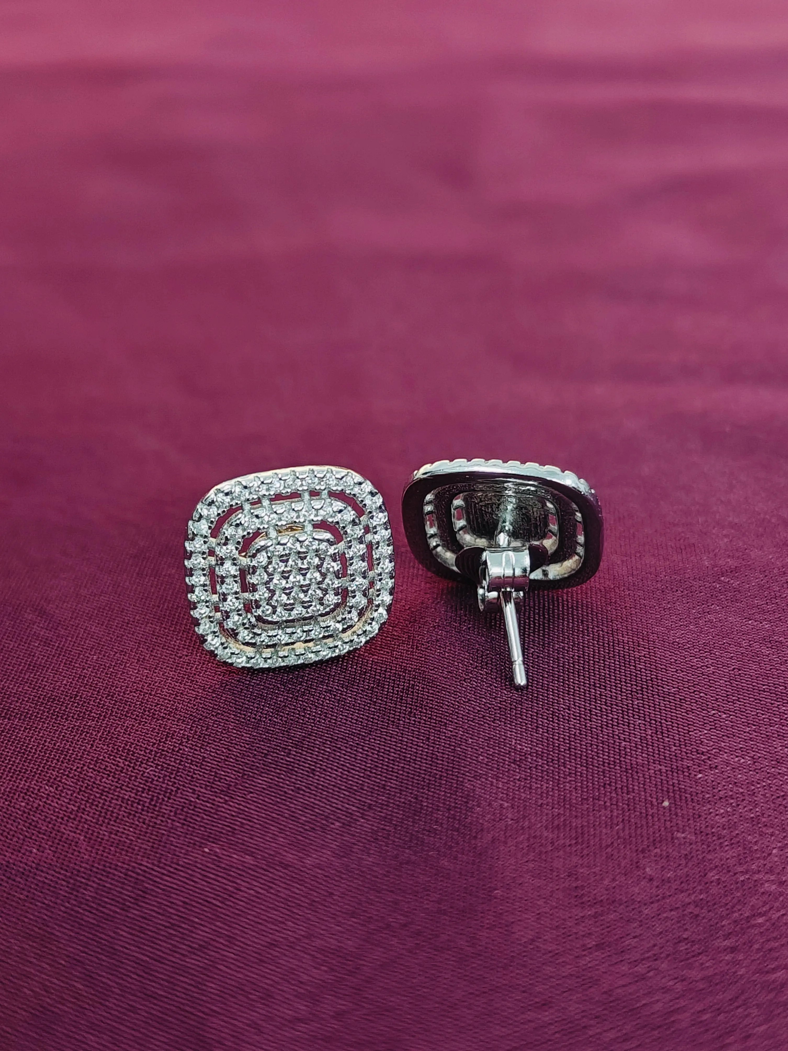 Silver square-shaped earrings on a purple fabric background