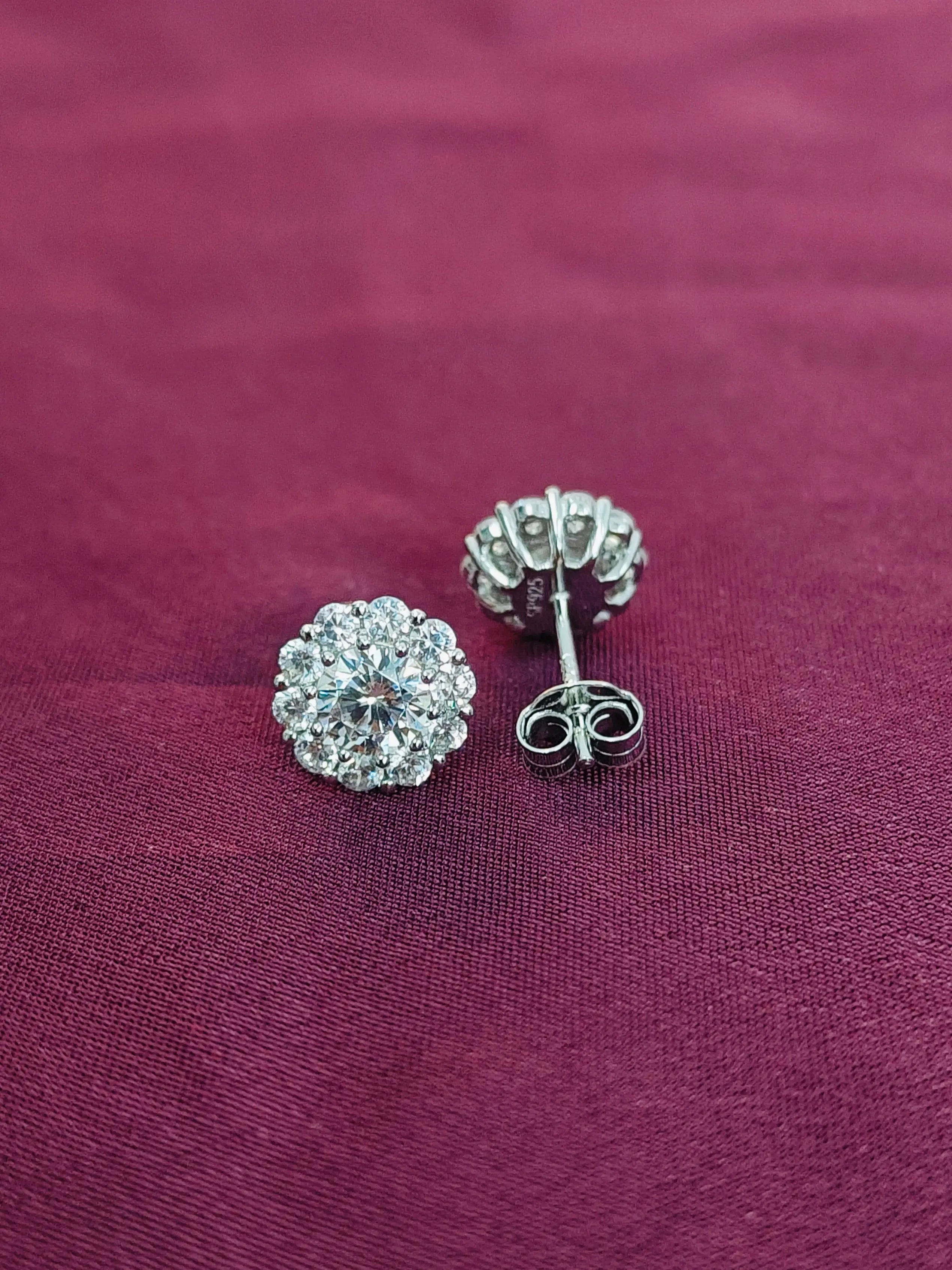 Silver earrings with clear gemstones on a purple fabric background