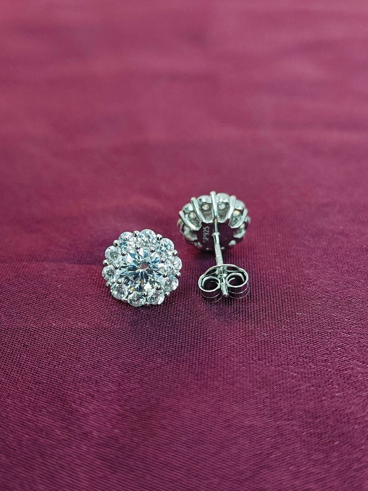 Silver floral earrings on a purple fabric background