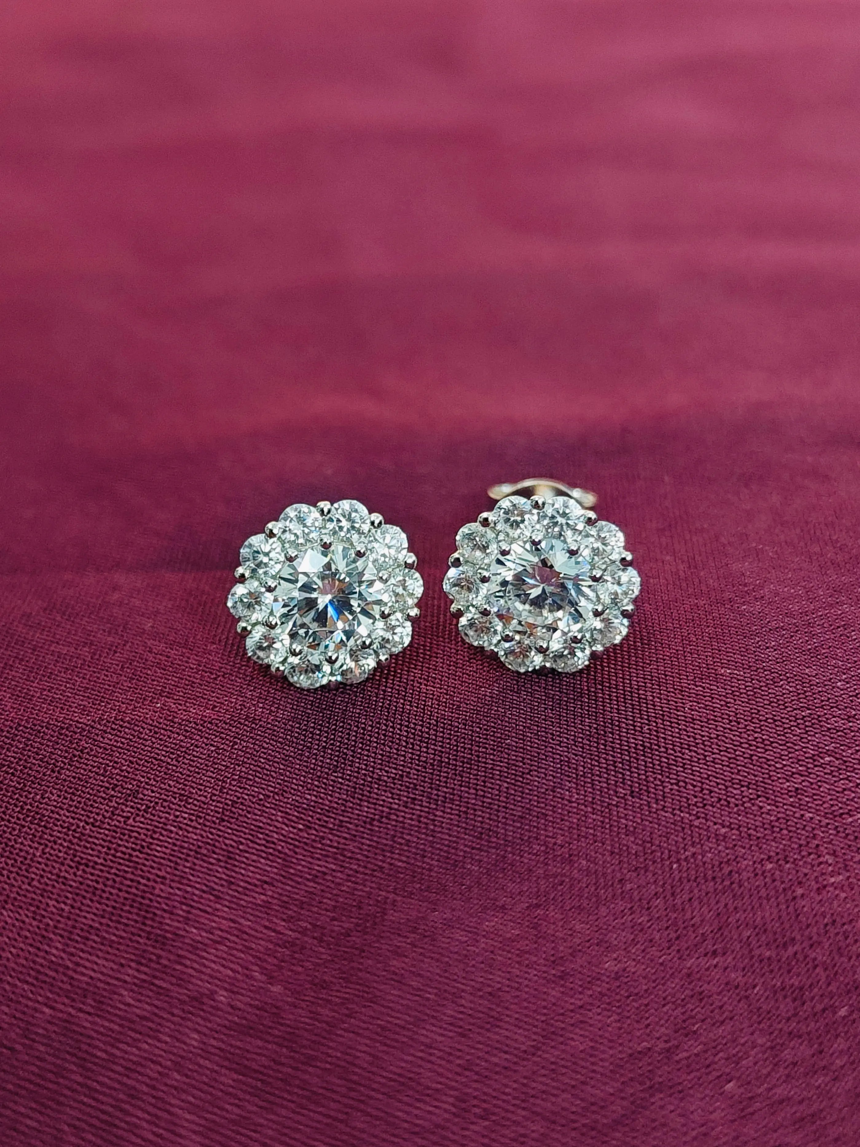 Pair of silver floral earrings on a maroon fabric background