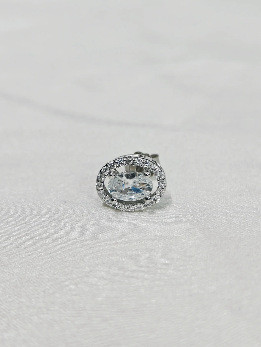 Silver earring with a large central gemstone on a white background