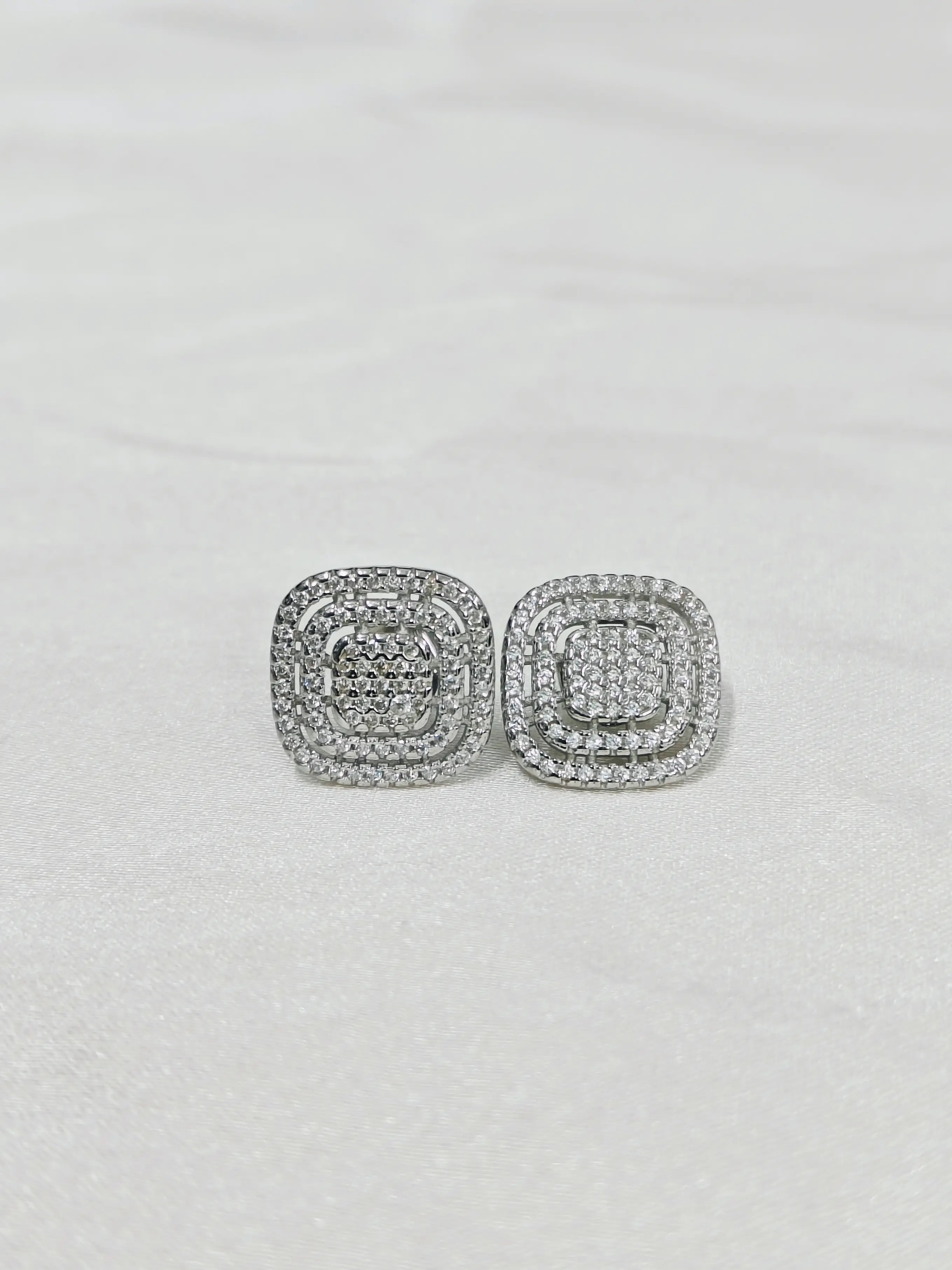 Silver square earrings with clear stones on a light gray background