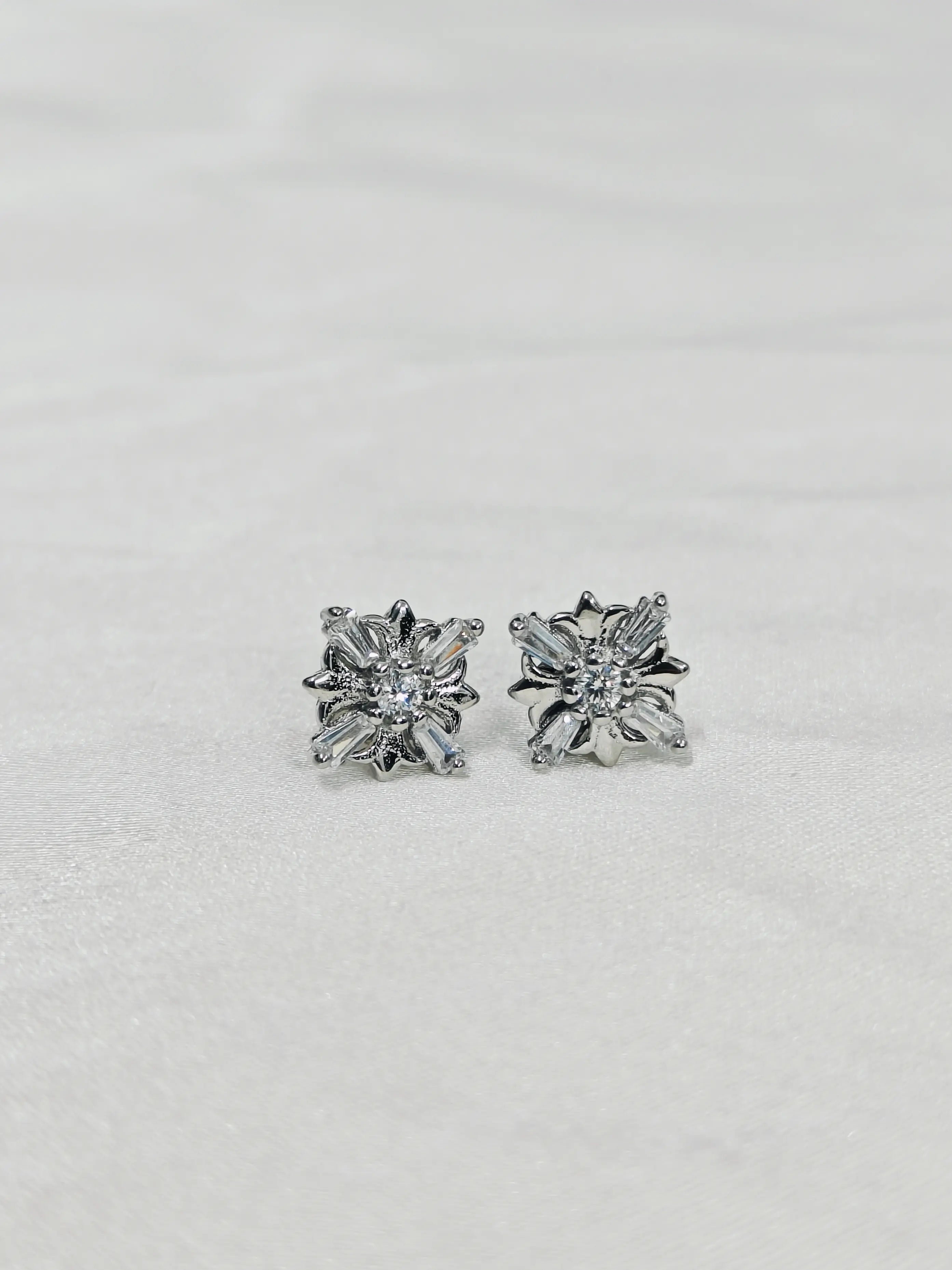 Pair of silver floral earrings on a light gray background