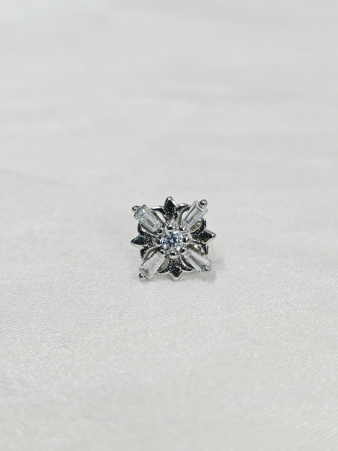 Single stud earring with clear gemstone on a light gray background