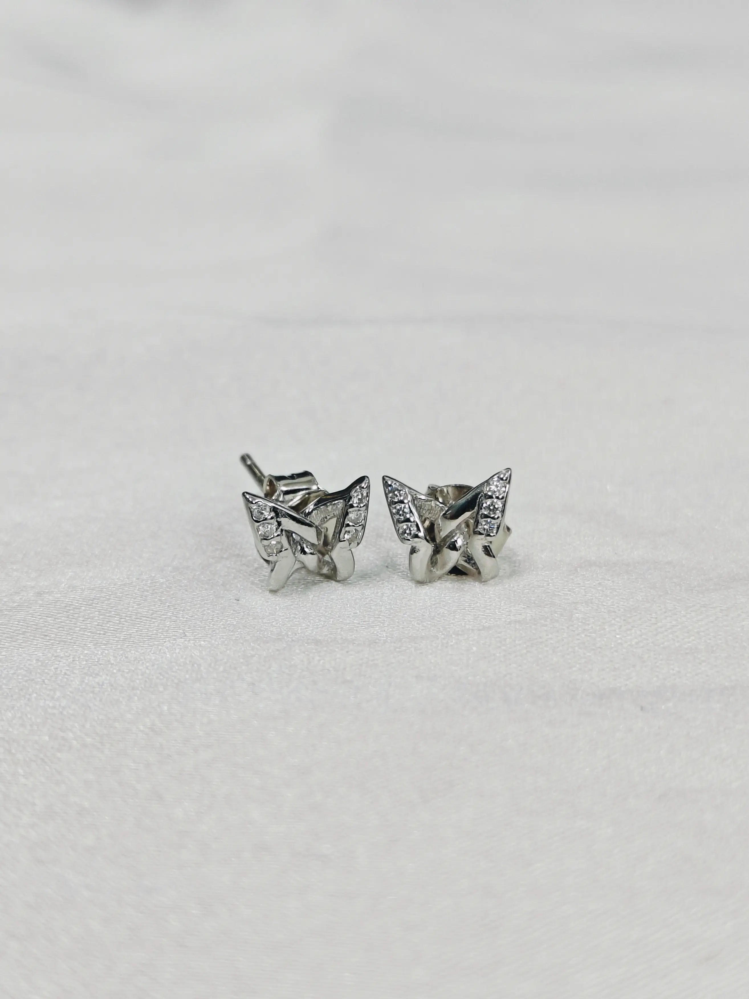 Butterfly-shaped silver earrings on a light gray background