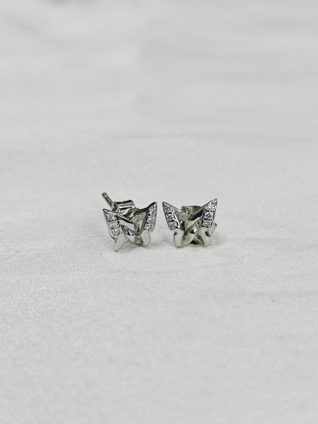 Butterfly-shaped silver earrings on a light gray background