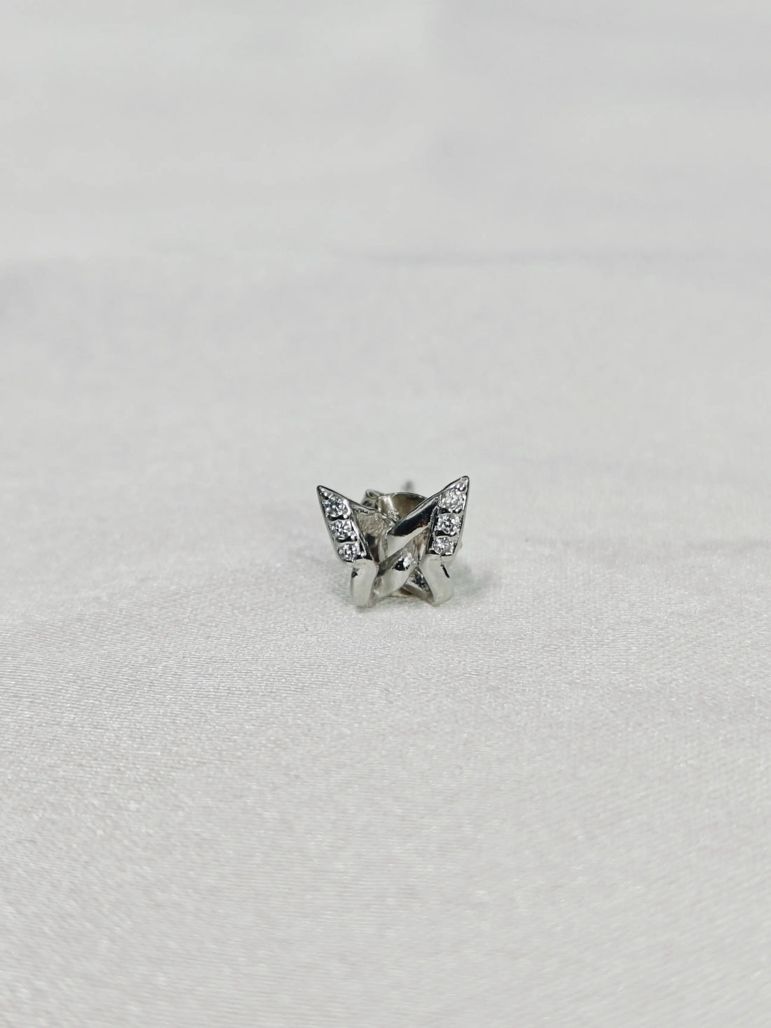 Silver butterfly-shaped earring on a light gray background