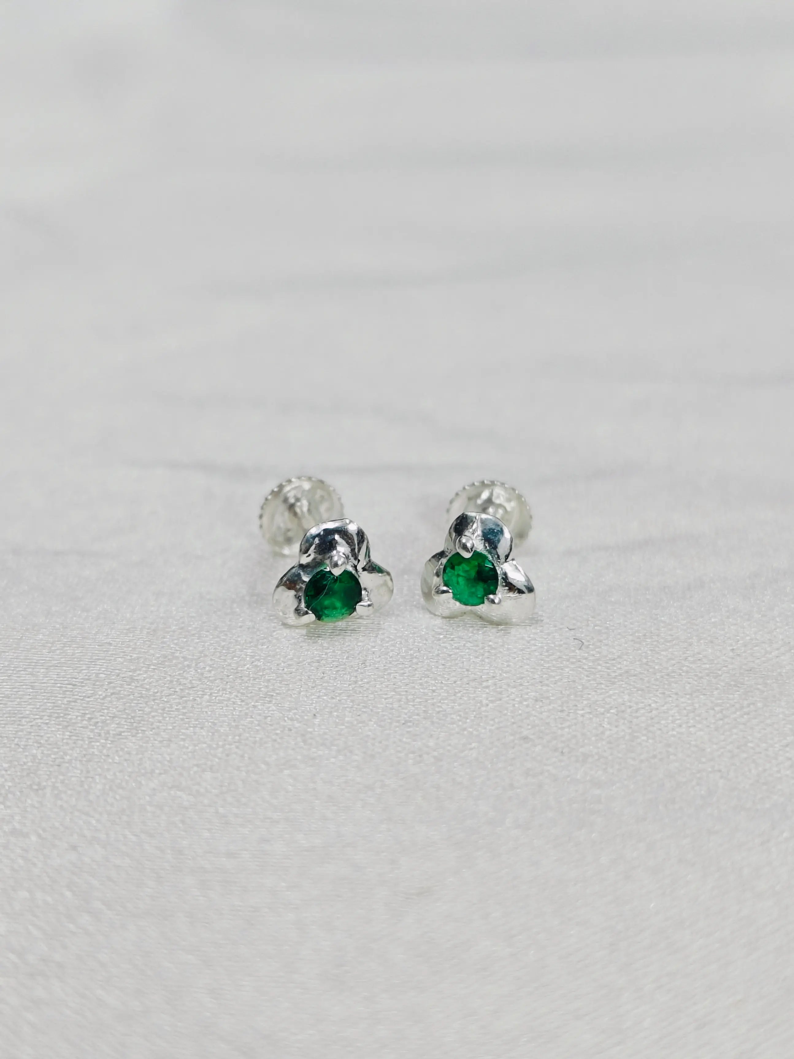 Silver earrings with green gemstones on a light gray background