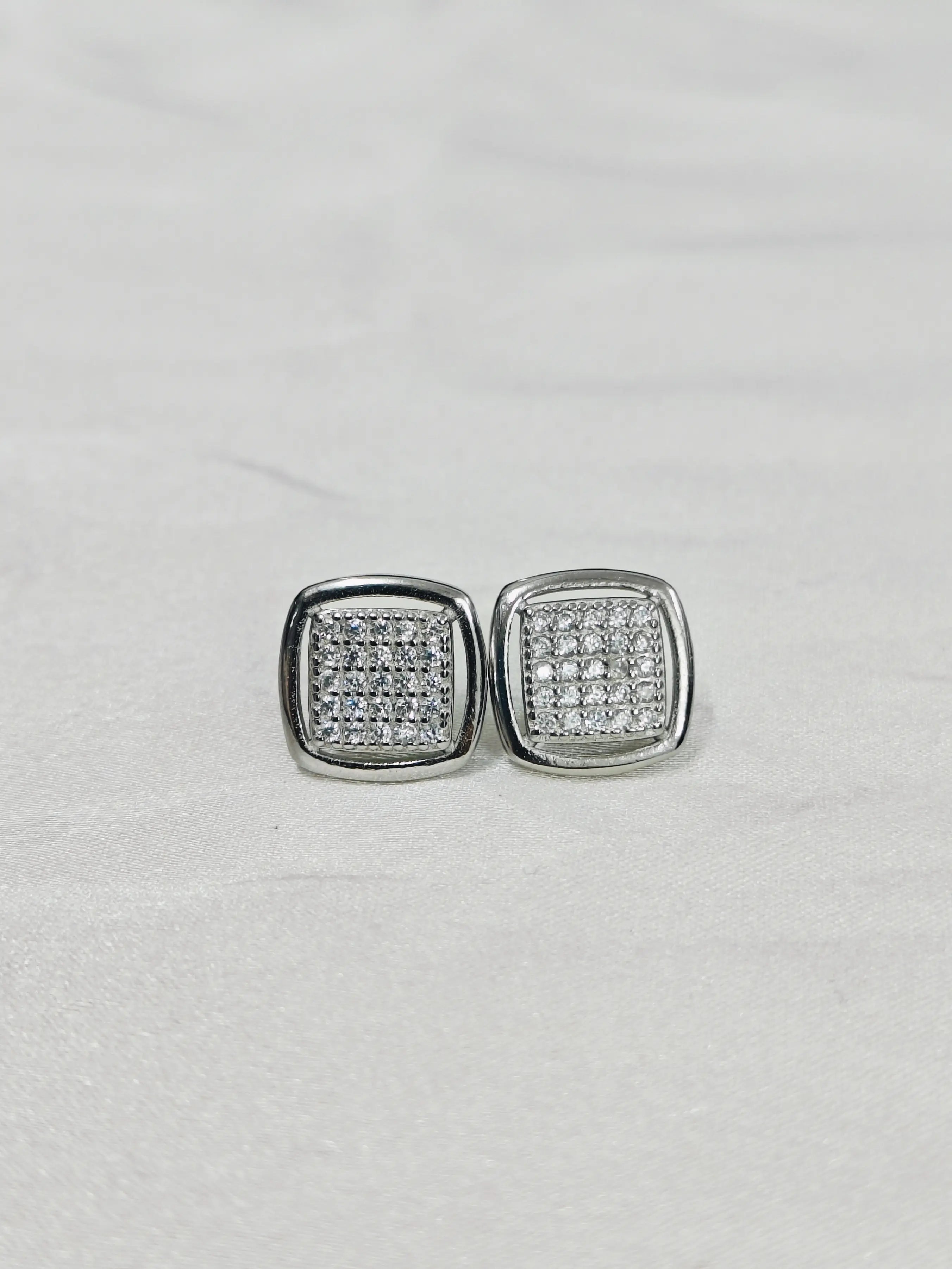 Pair of silver square earrings with clear stones on a light gray background