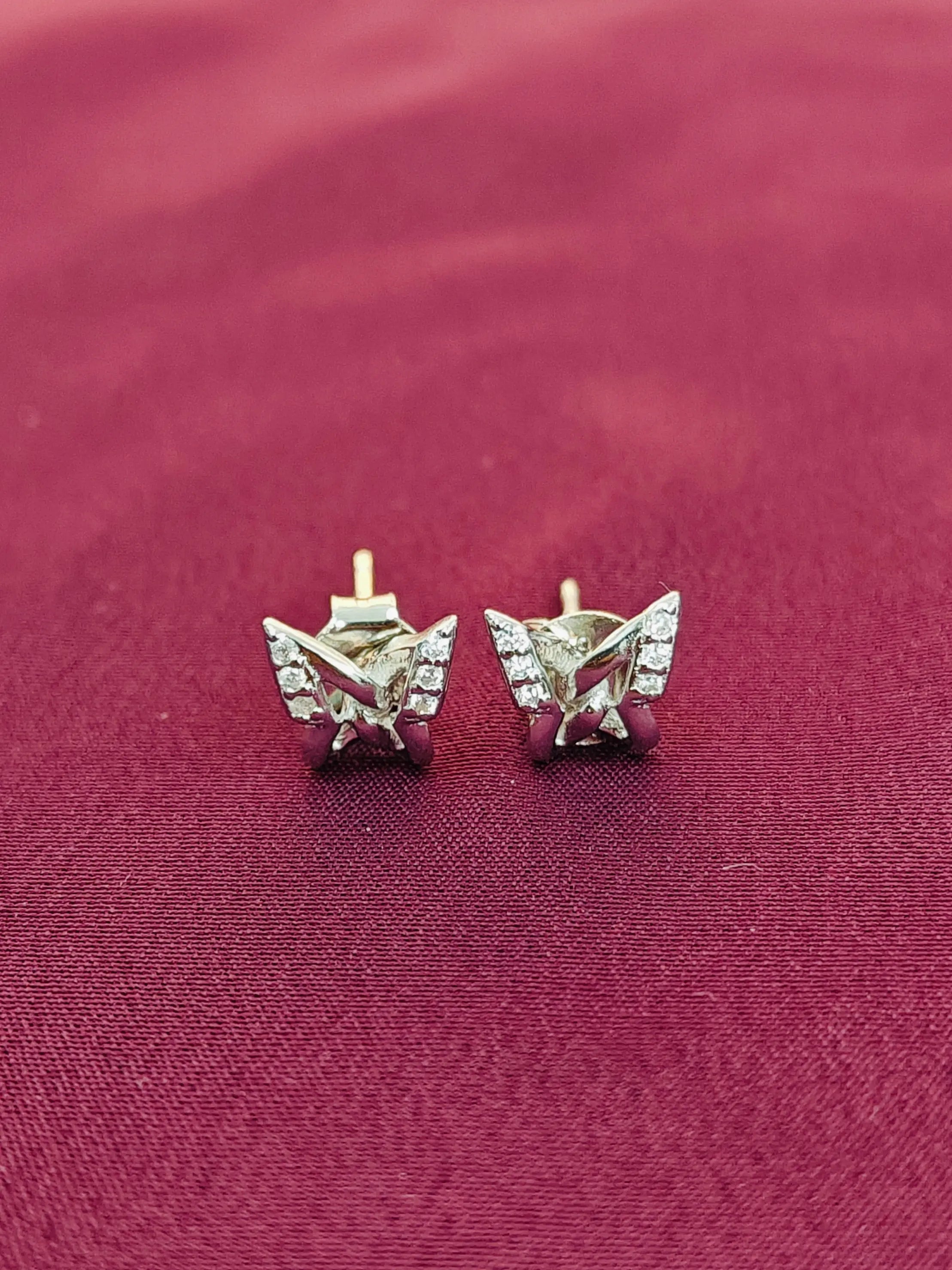 Gold butterfly earrings on a red fabric background