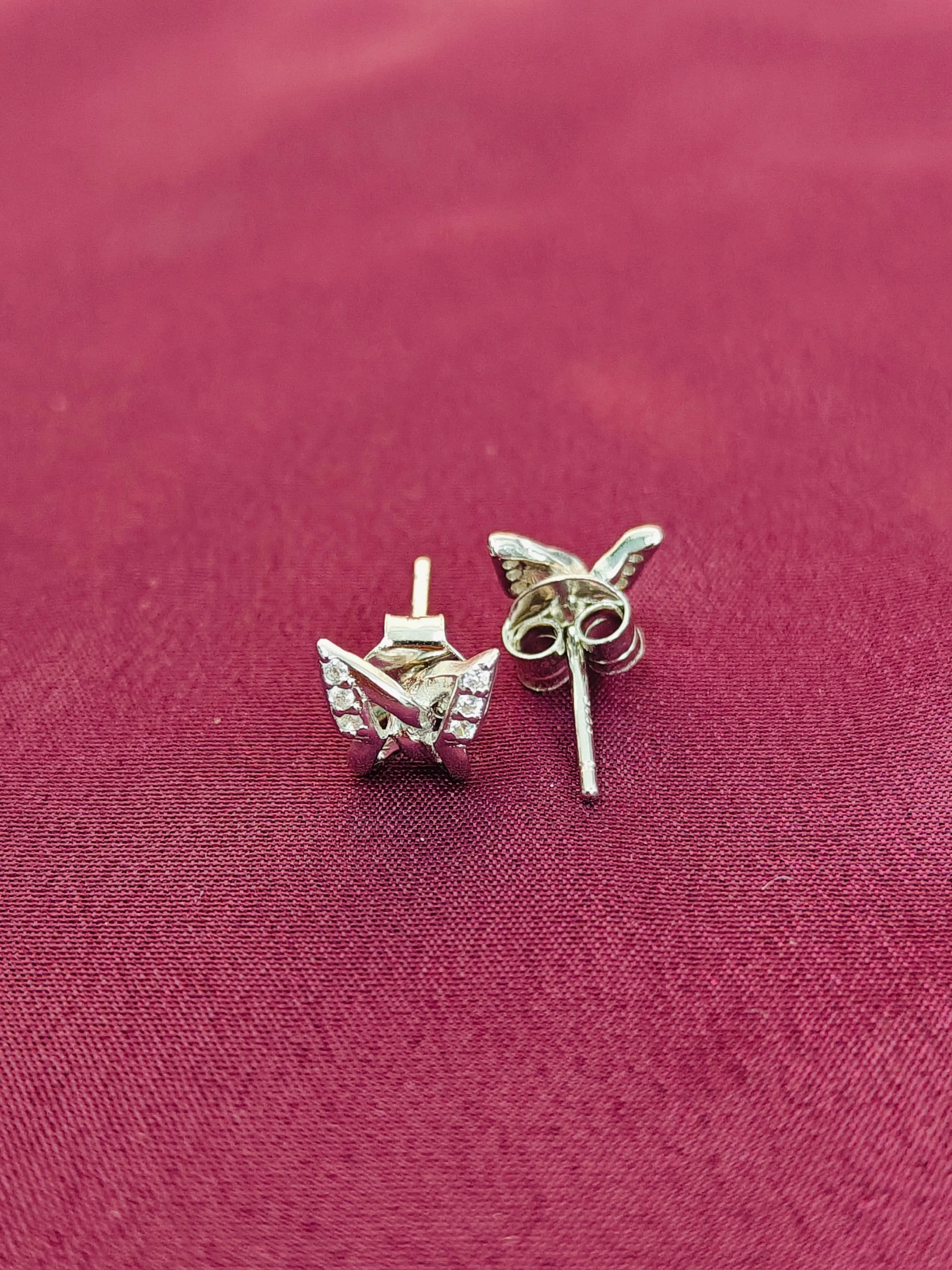 Silver butterfly earrings on a red fabric background