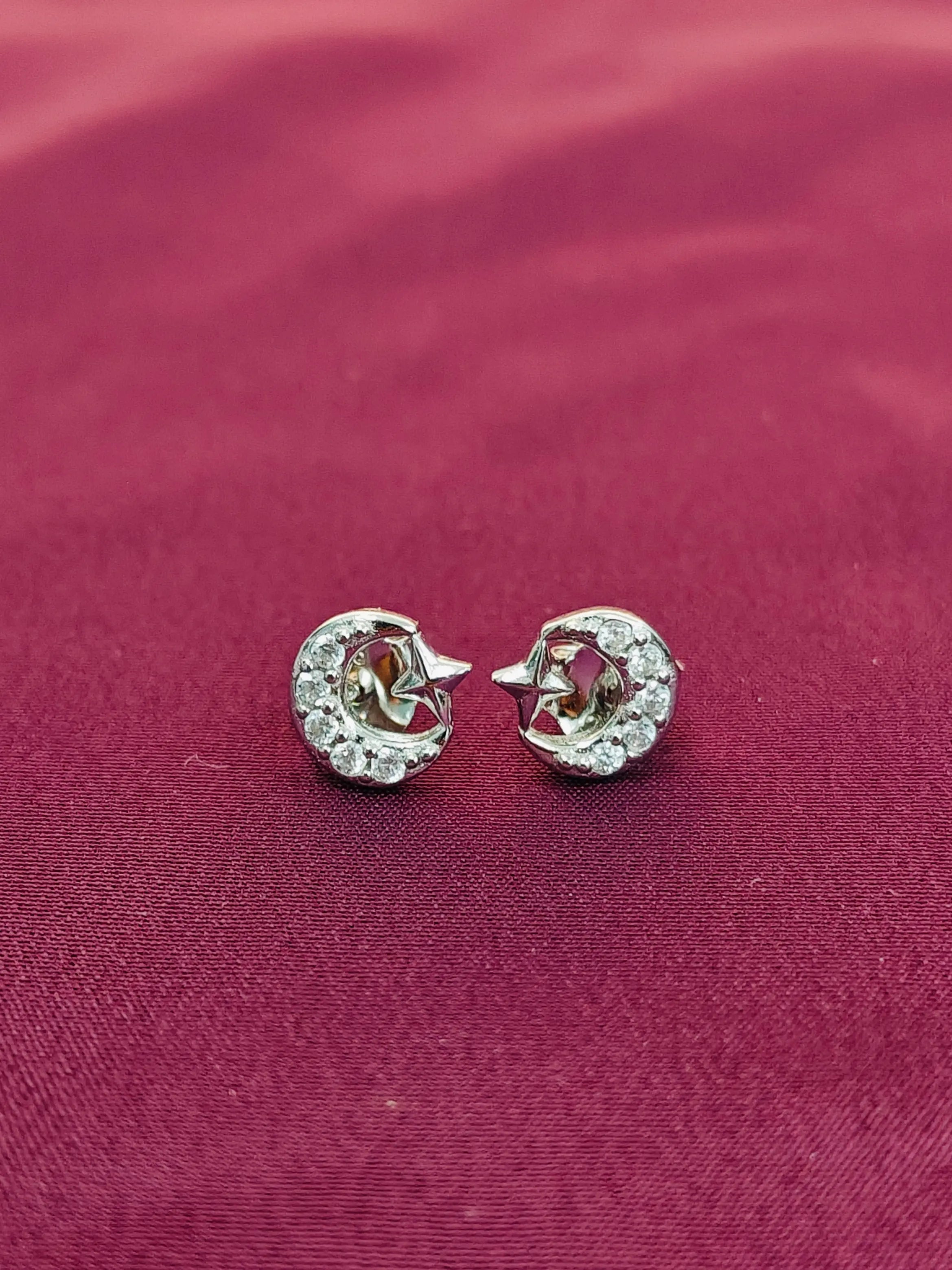 Pair of silver earrings with gemstones on a red fabric background