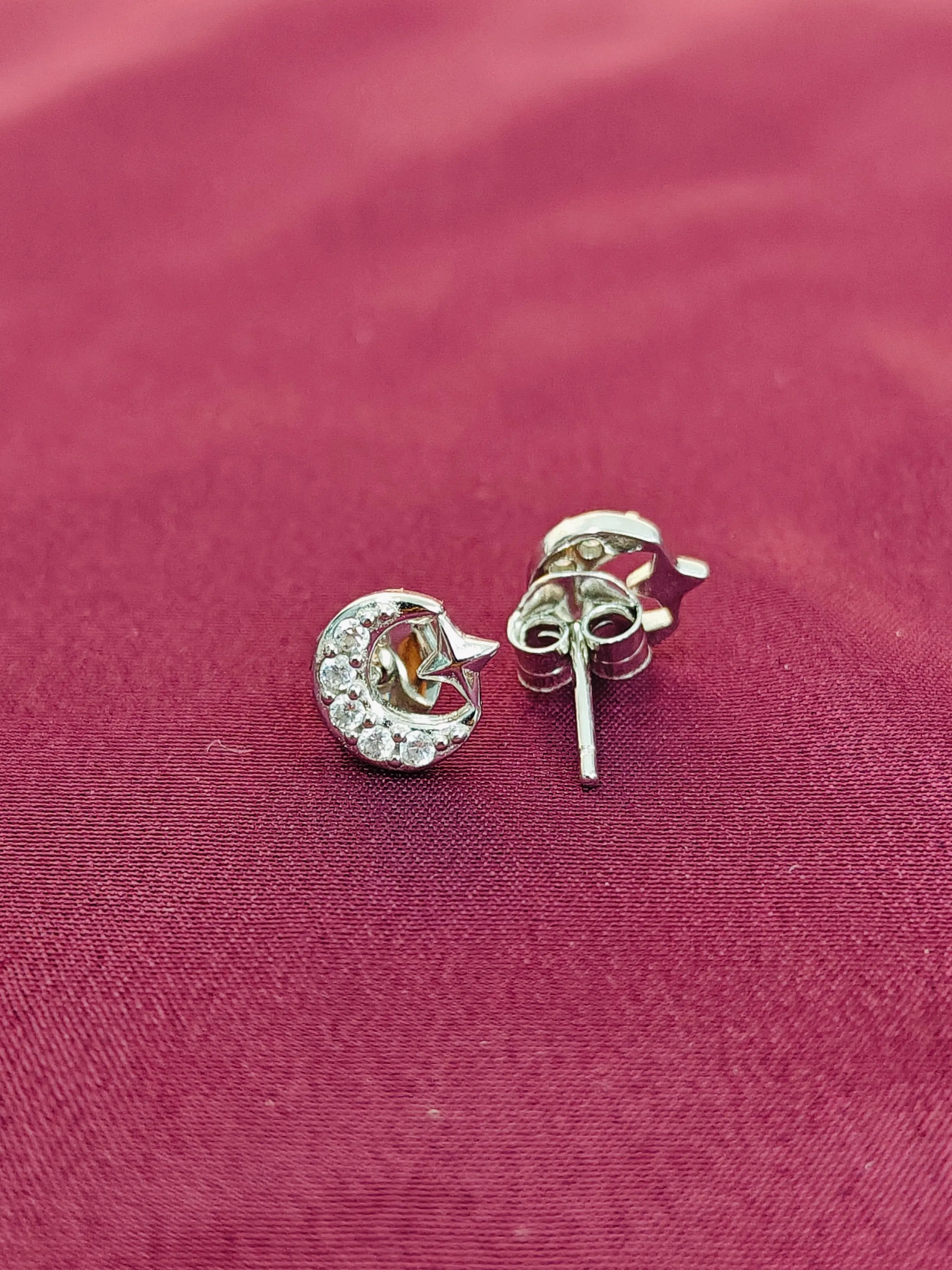 Silver earrings with gemstones on a red fabric background