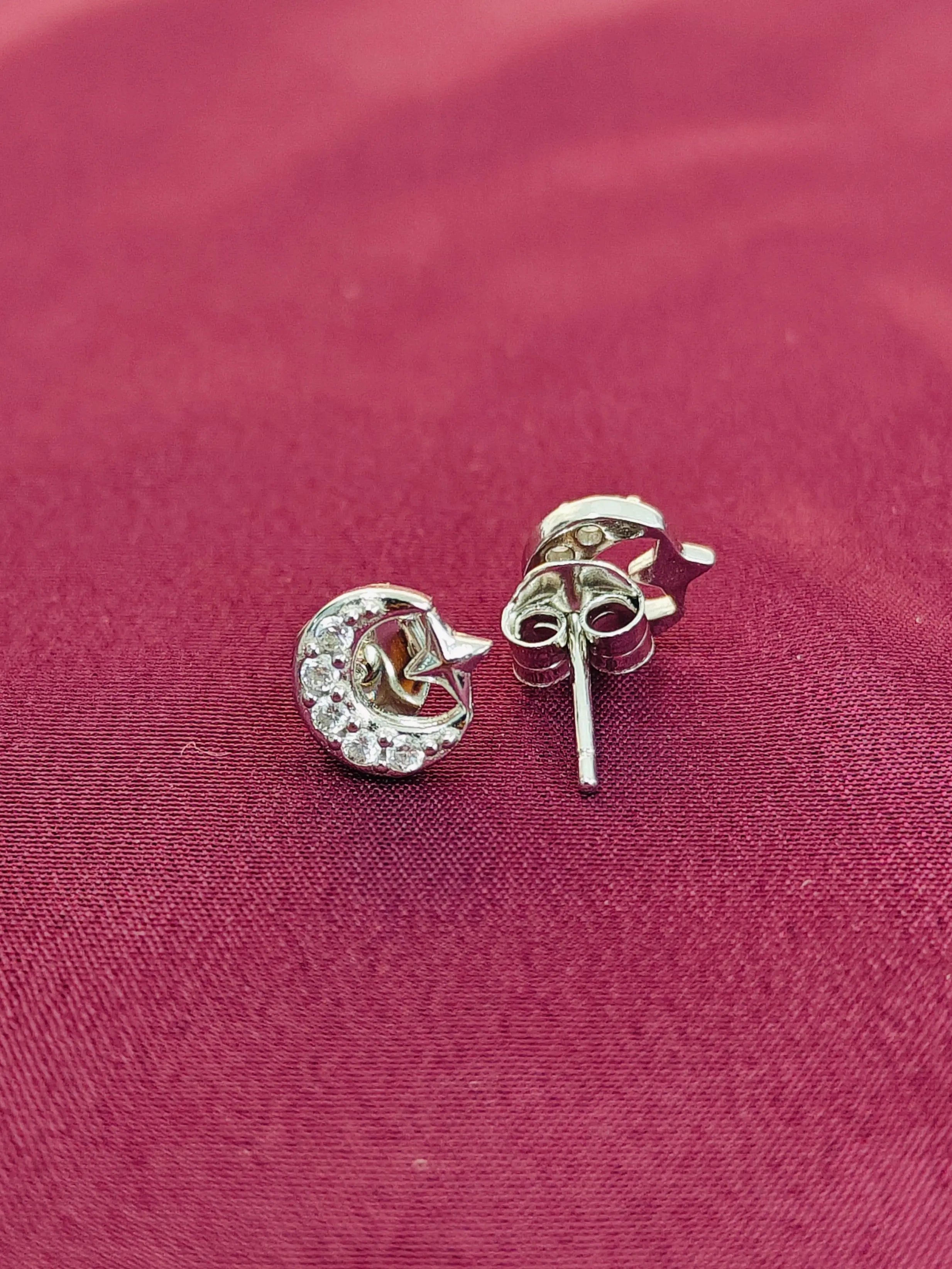 Silver stud earrings with clear stones on a red fabric background