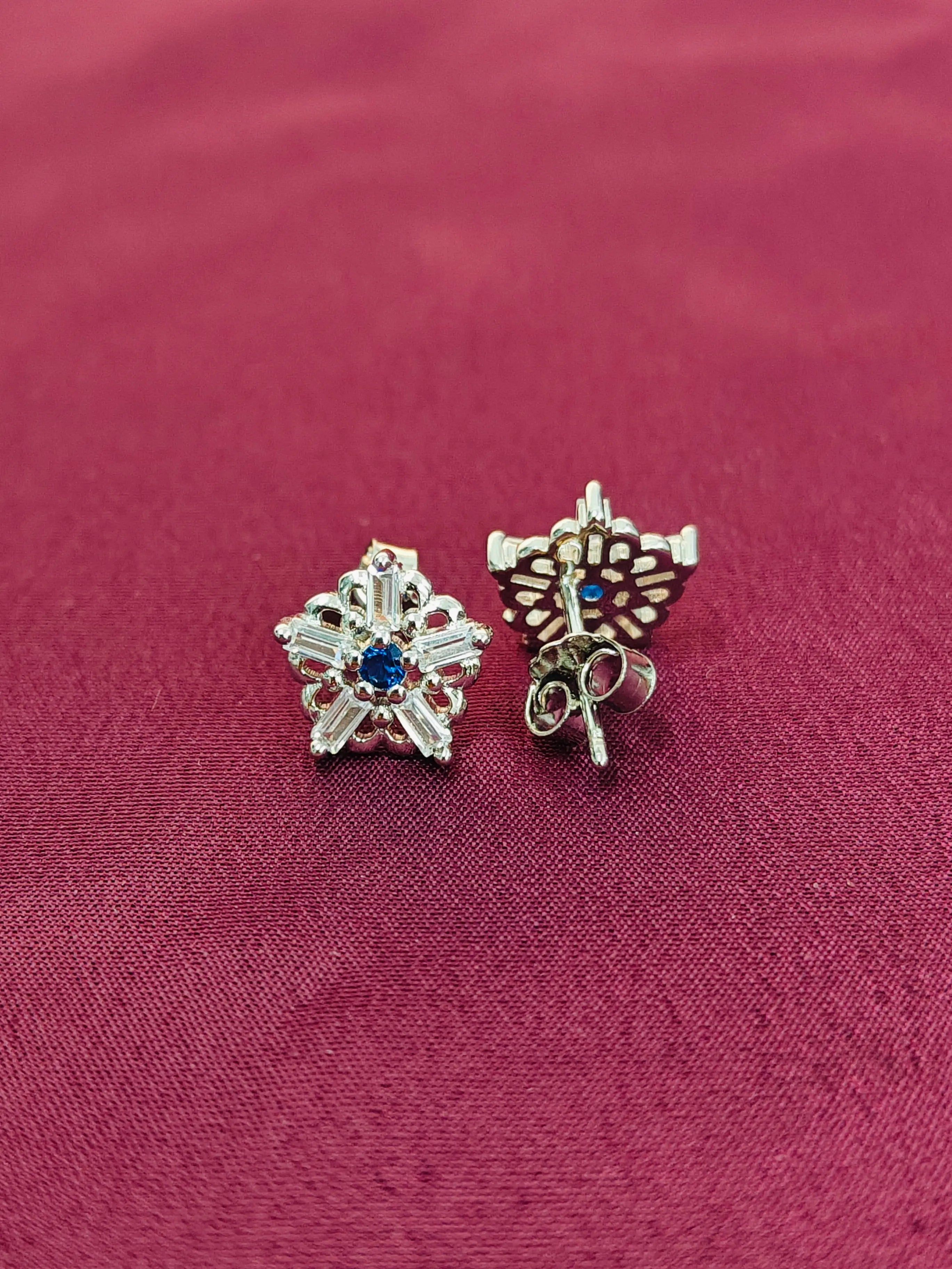 Pair of silver earrings with gemstones on a red fabric background