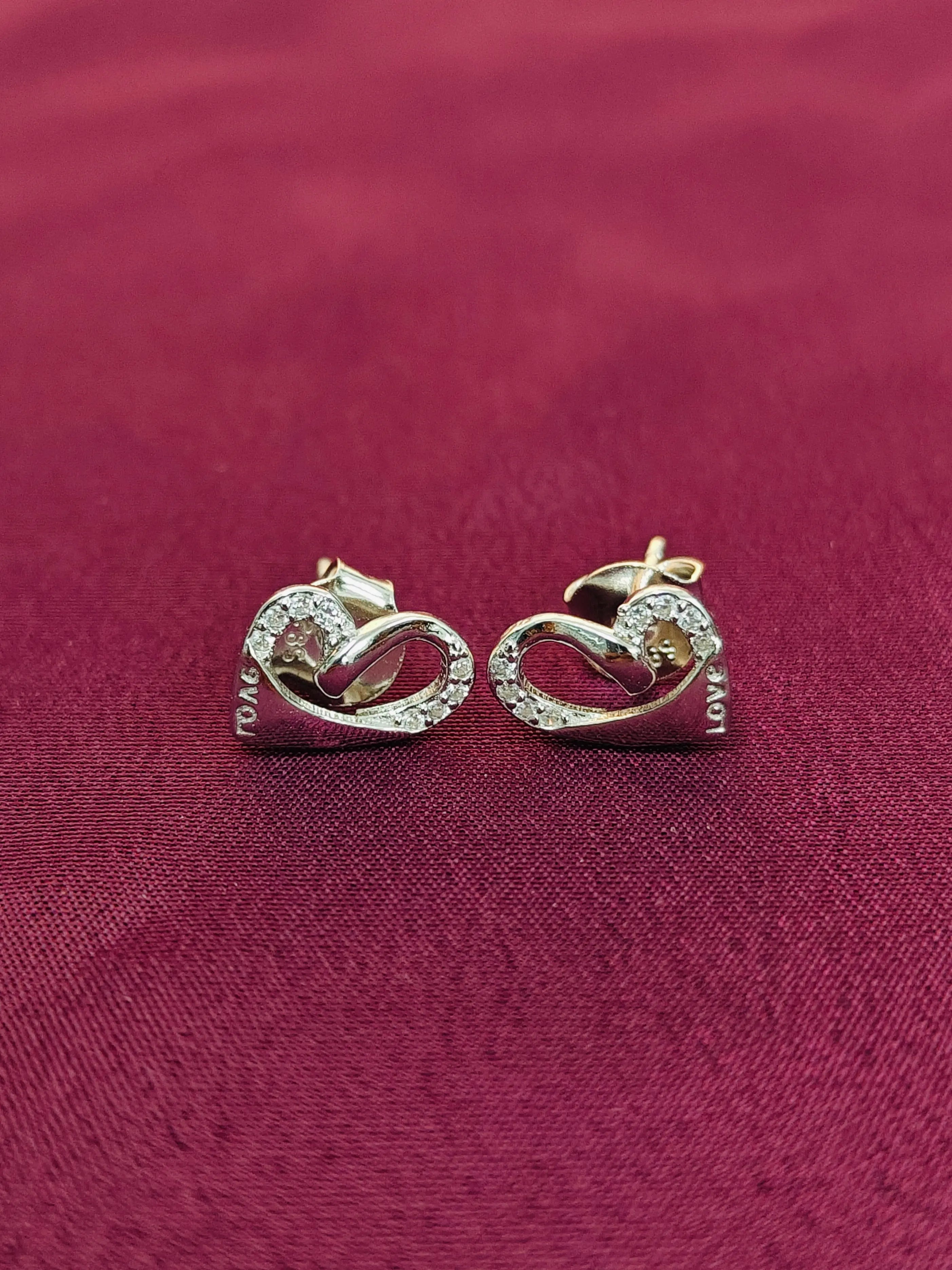 Pair of gold earrings on a red fabric background