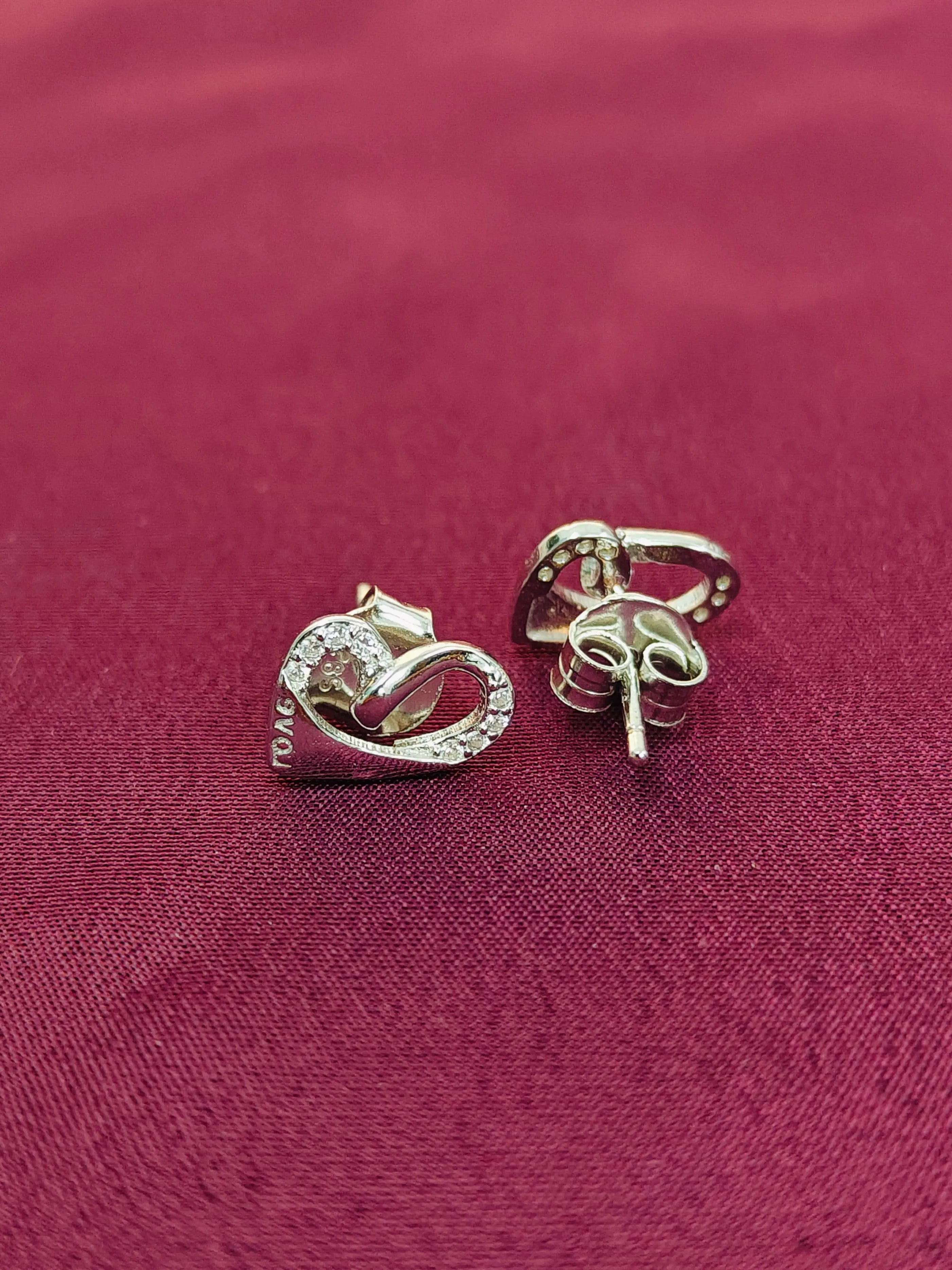 Pair of silver earrings on a red fabric background