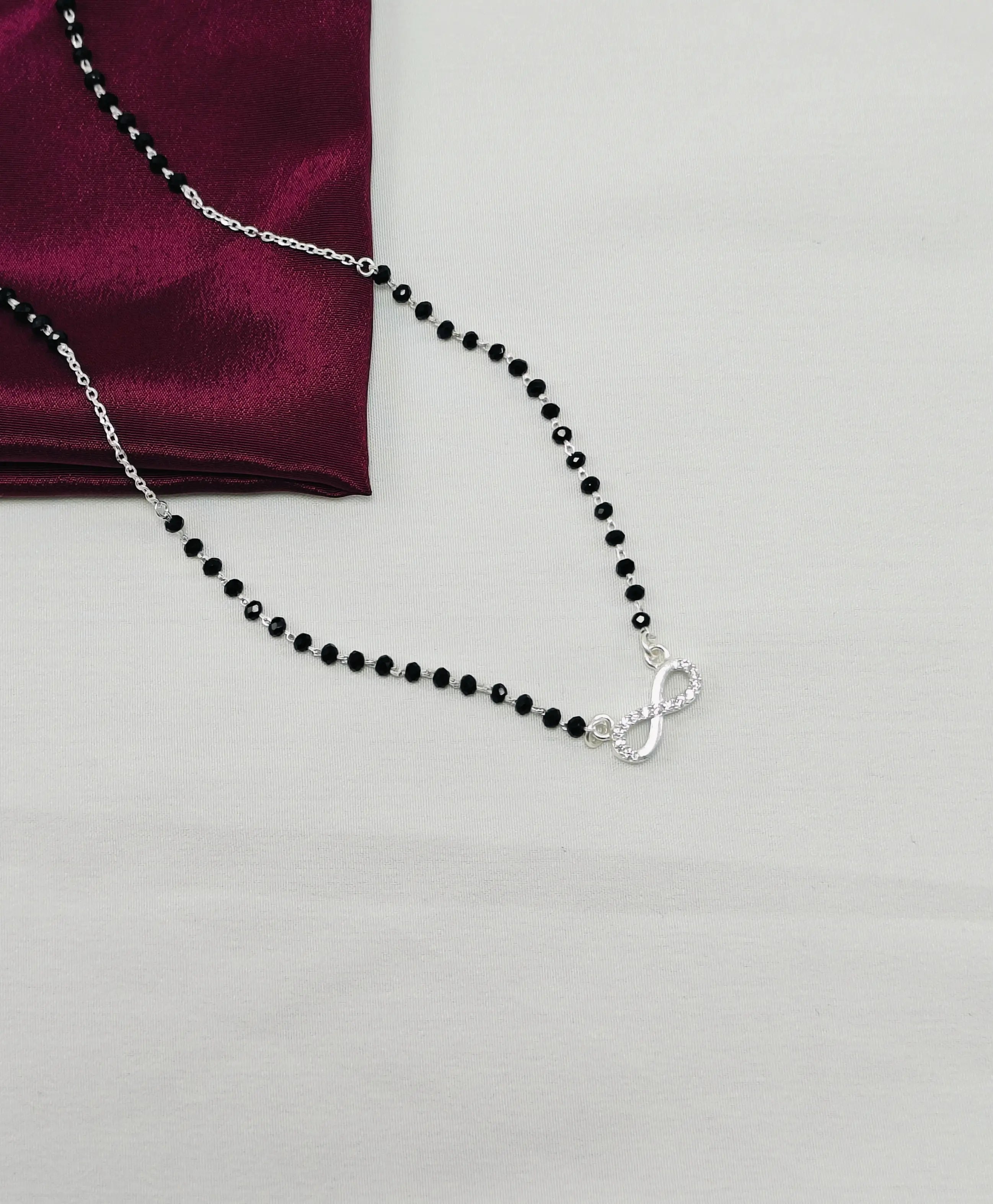 Black beaded necklace with a silver clasp on a white background