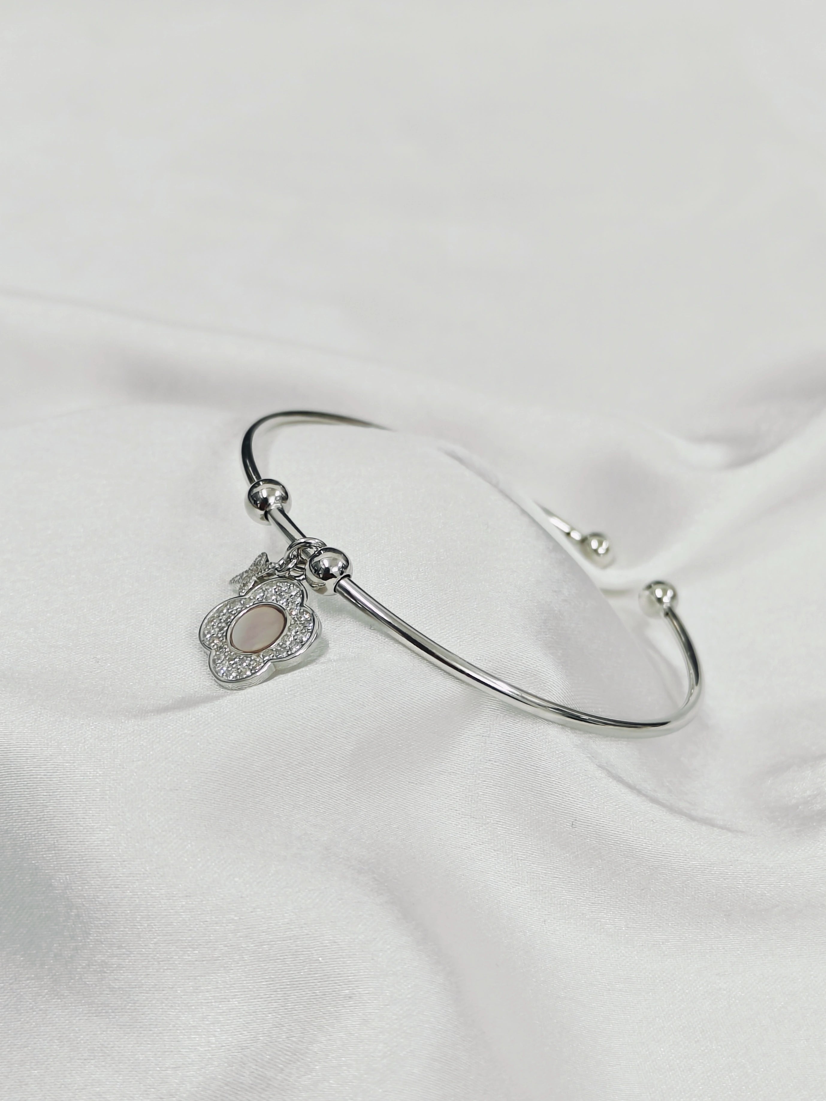 Silver bracelet with a heart-shaped charm on a white fabric background