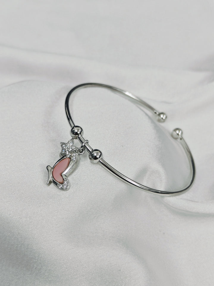 Silver bracelet with a pink fish charm on a white background