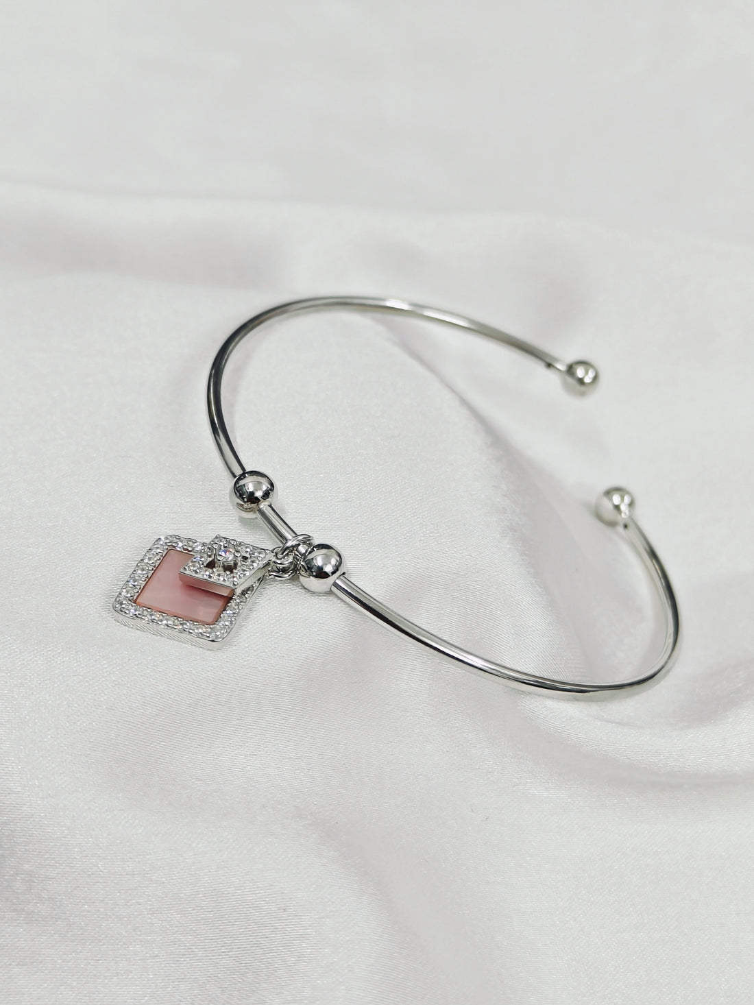 Silver bracelet with a square charm on a white background
