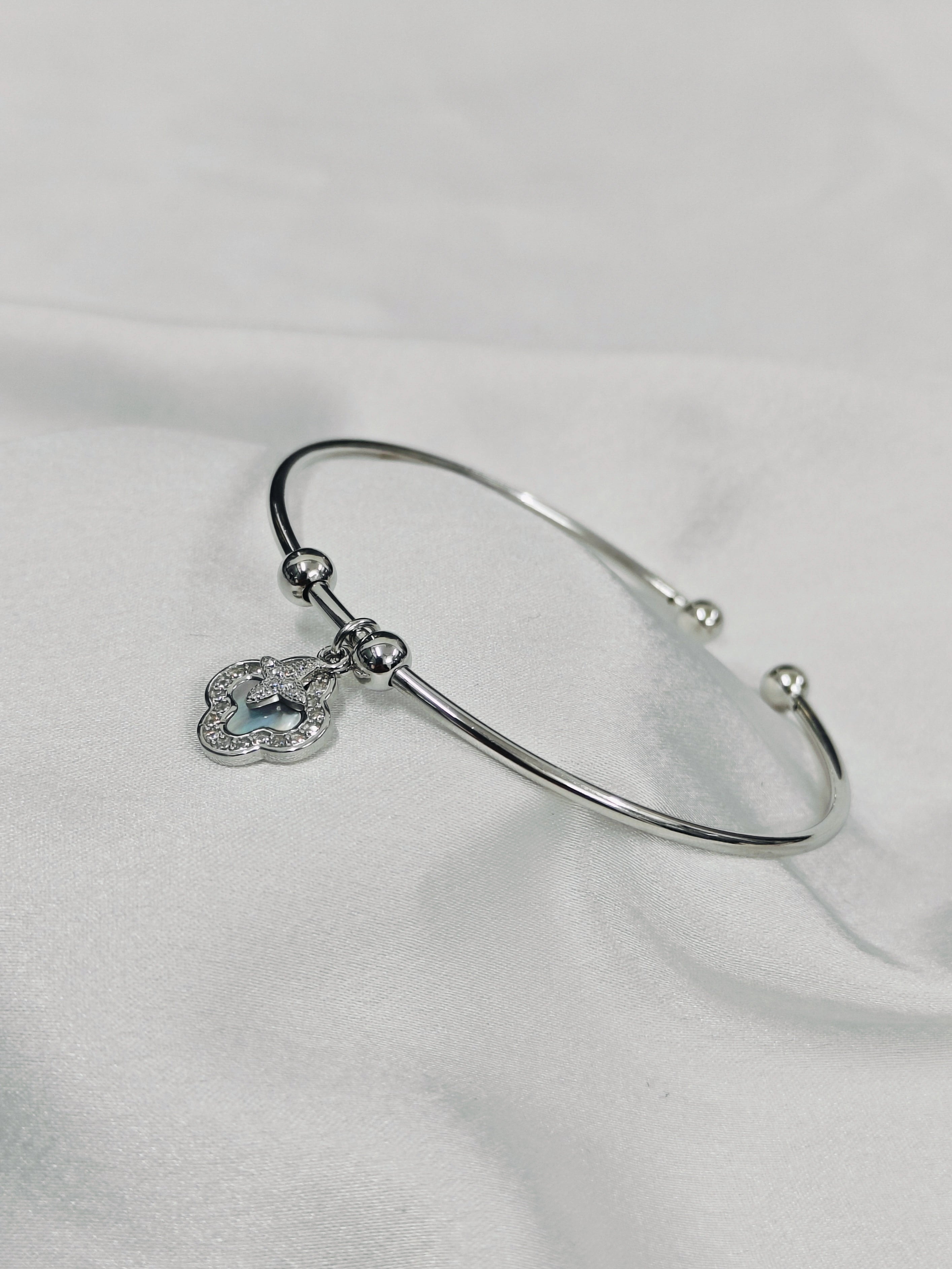 Silver bracelet with a heart-shaped charm on a white fabric background
