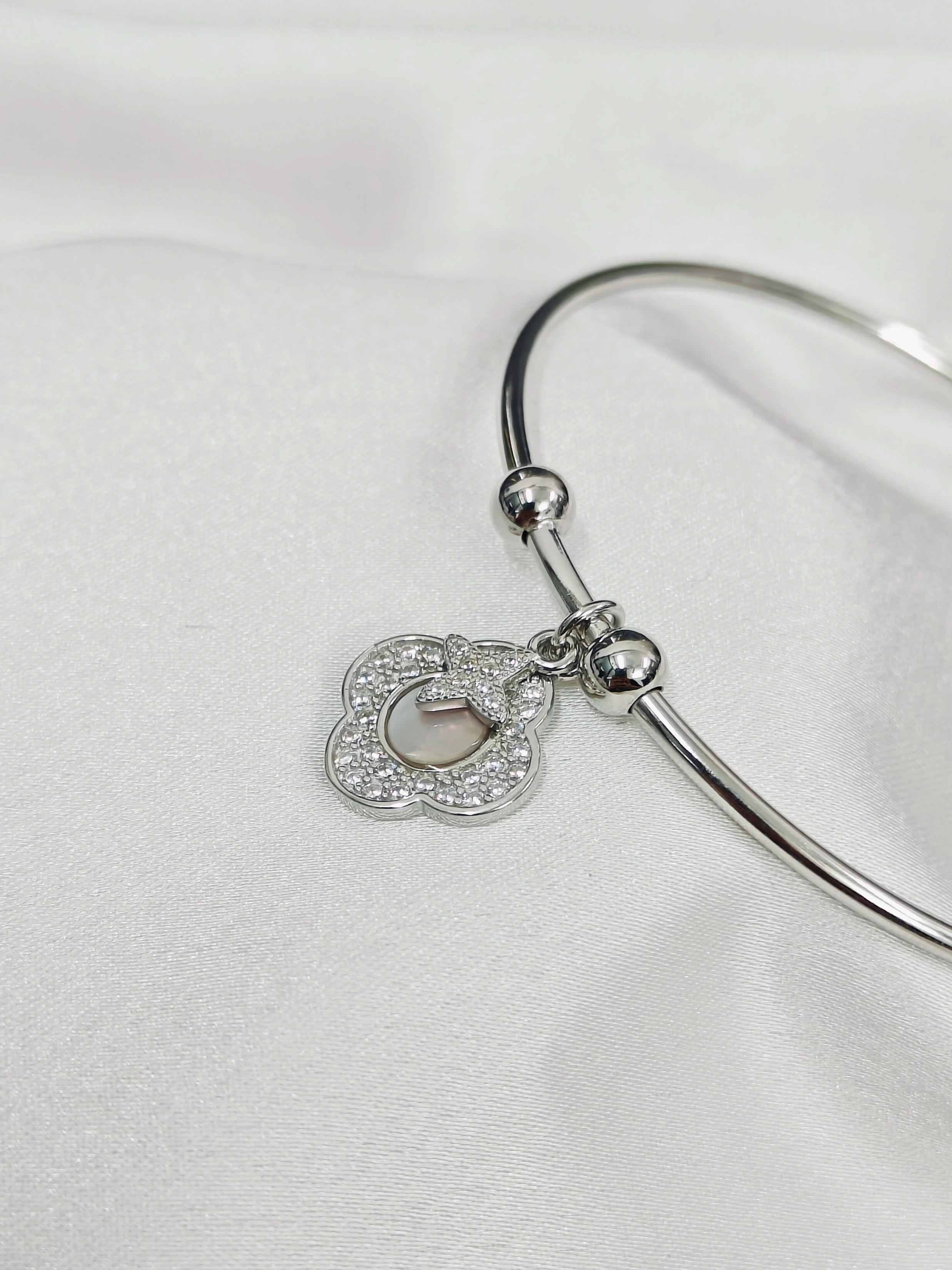 Silver bangle with a heart-shaped charm on a white background