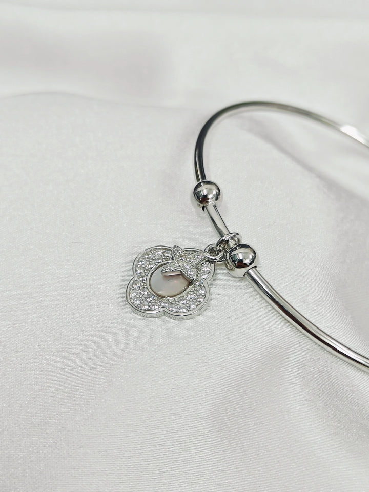 Silver bangle with a heart-shaped charm on a white background