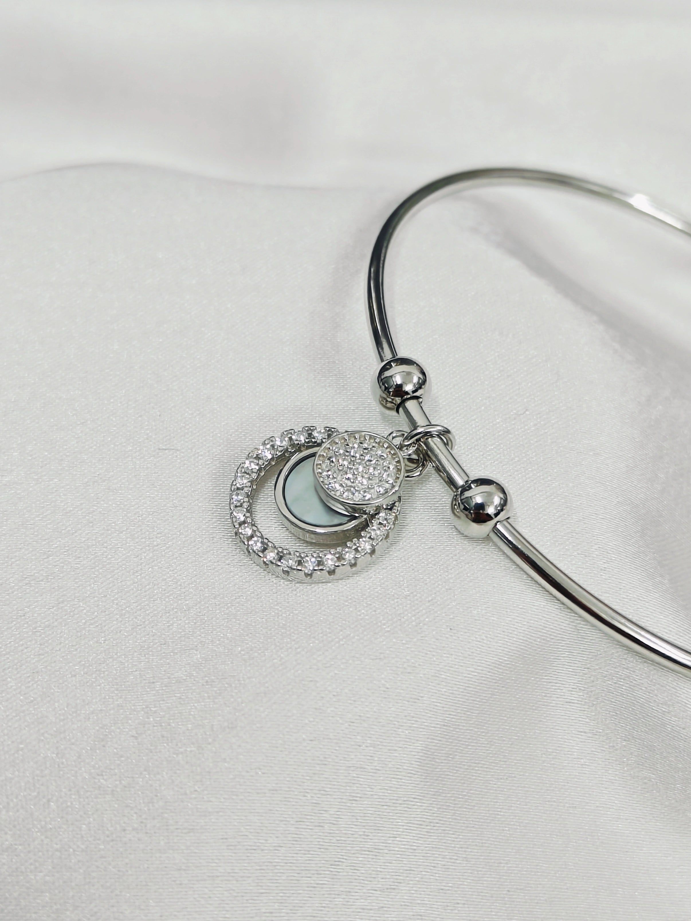 Silver bracelet with heart-shaped charm on a white background
