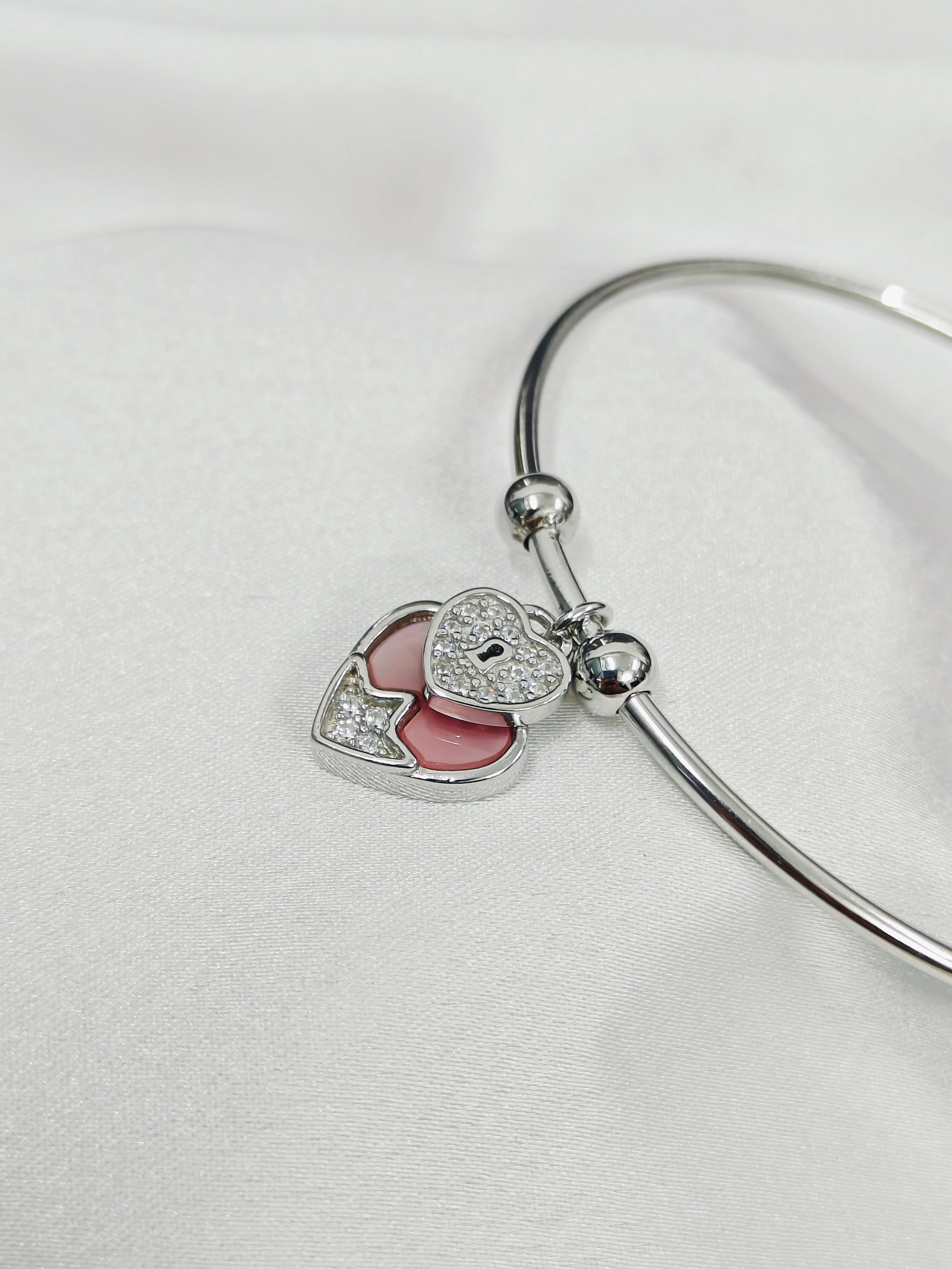 Silver bangle with heart-shaped charms on a white background
