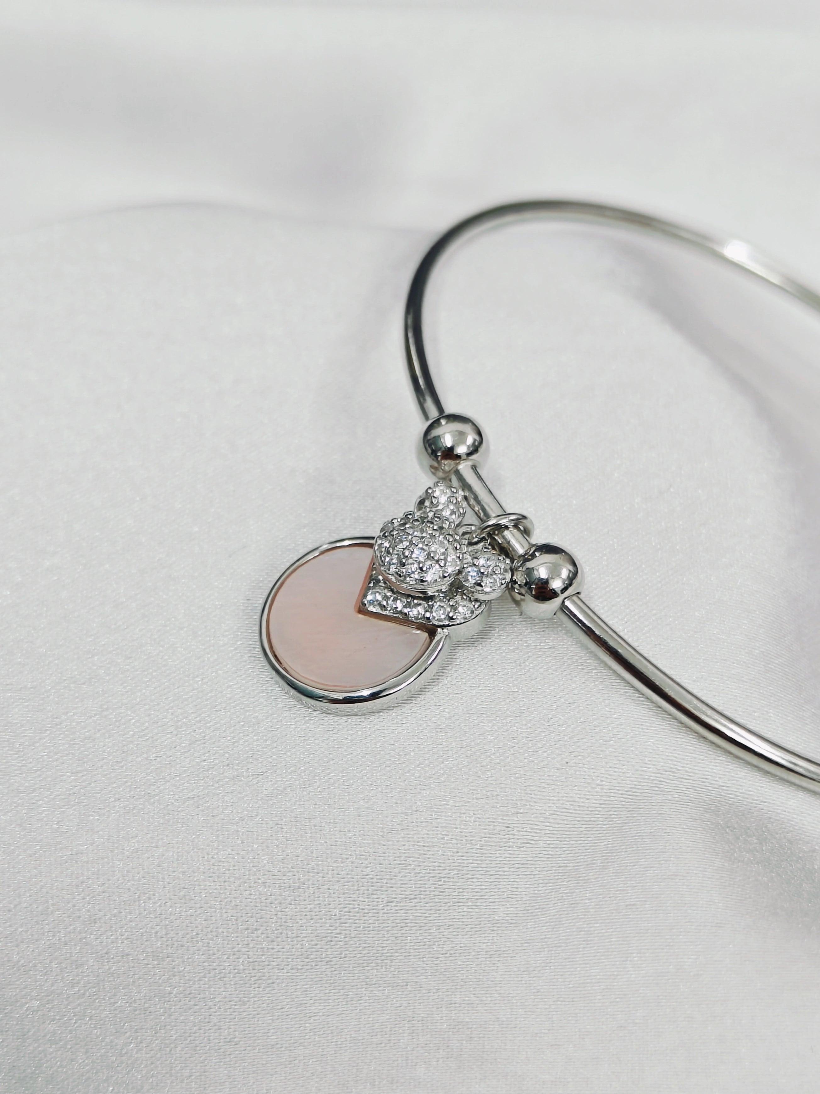 Silver bracelet with a heart-shaped charm on a light gray background