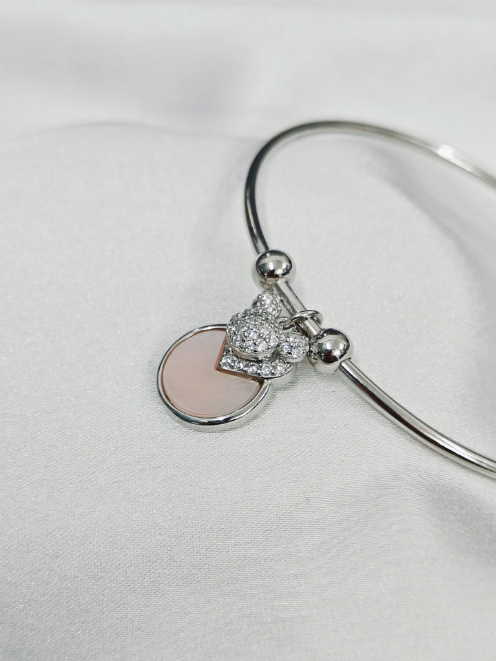 Silver bracelet with a heart-shaped charm on a light gray background