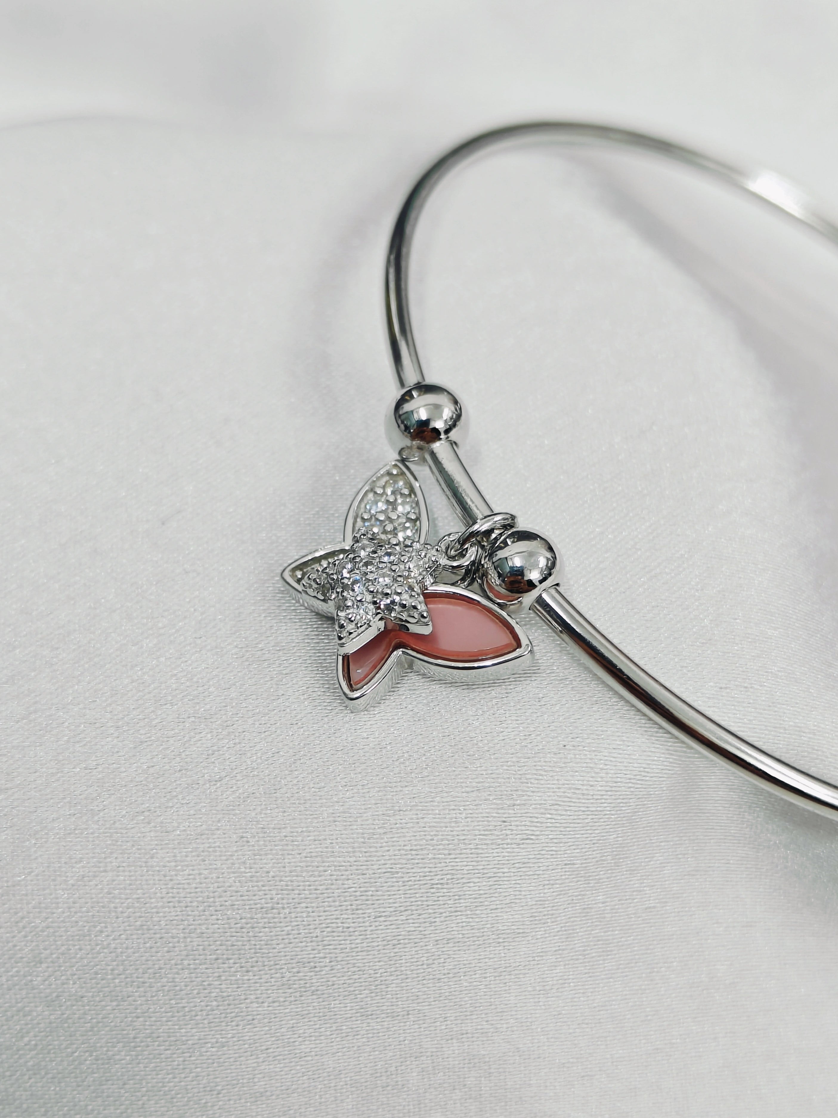Silver bracelet with a butterfly charm on a light gray background