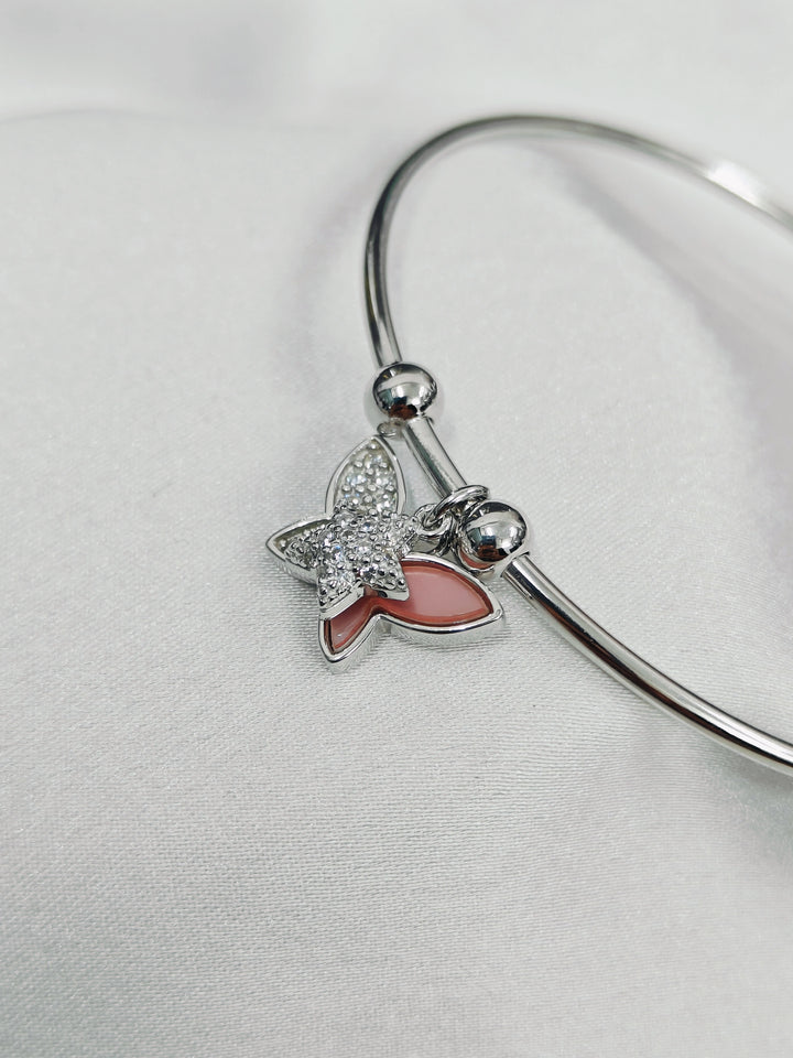 Silver bracelet with a butterfly charm on a light gray background