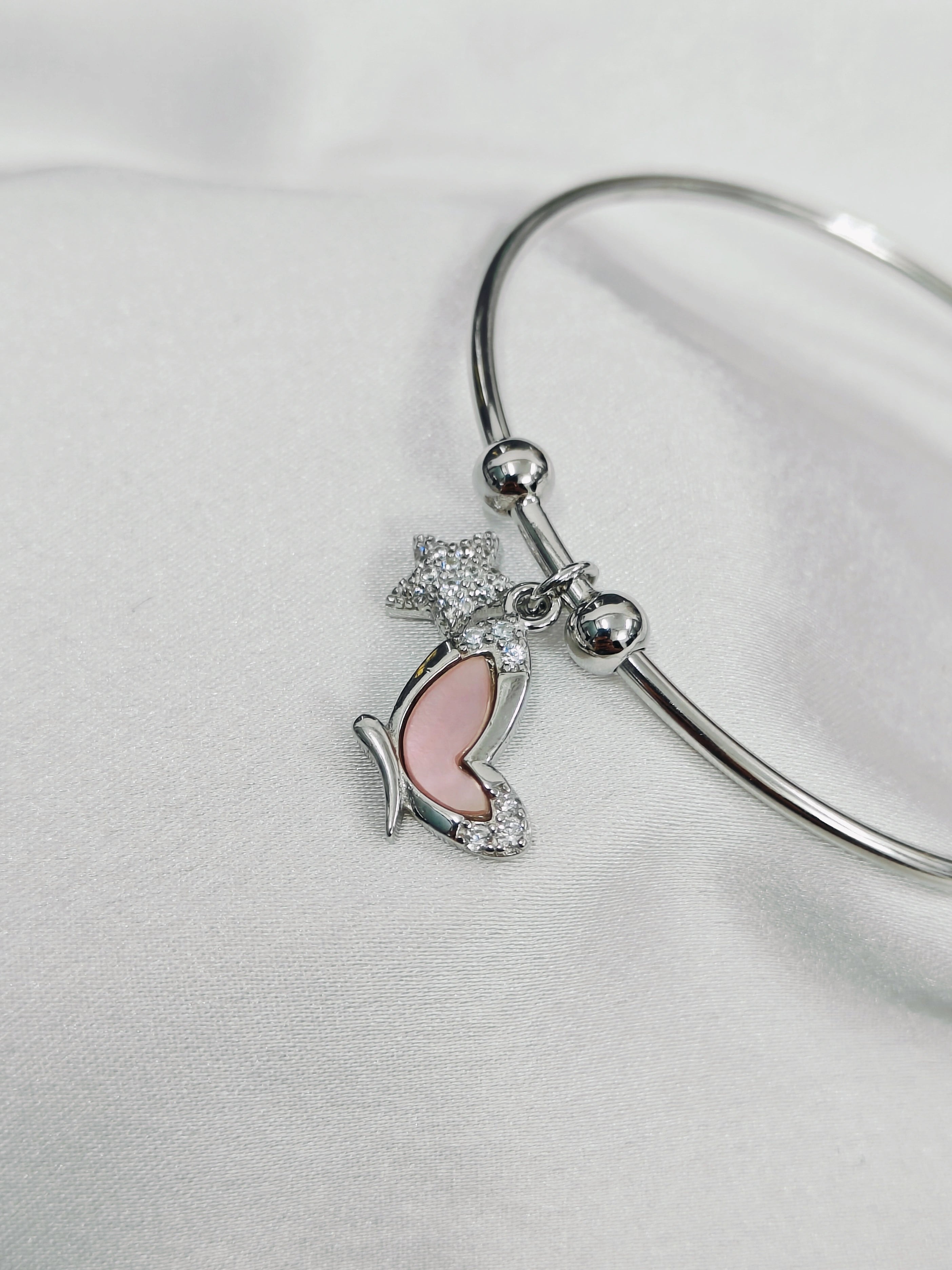 Silver bangle with butterfly and heart charm on a light gray background