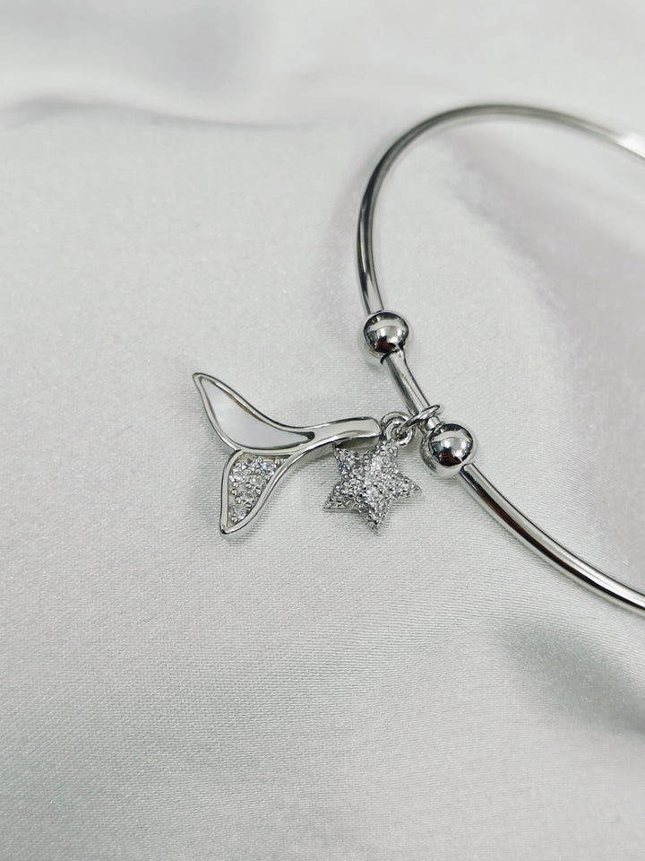 Silver bracelet with star and leaf charms on a light gray background