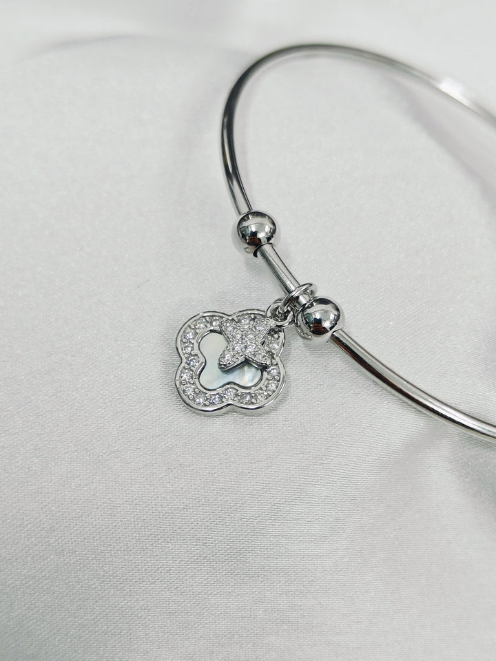 Silver bangle with a heart-shaped charm on a light gray background