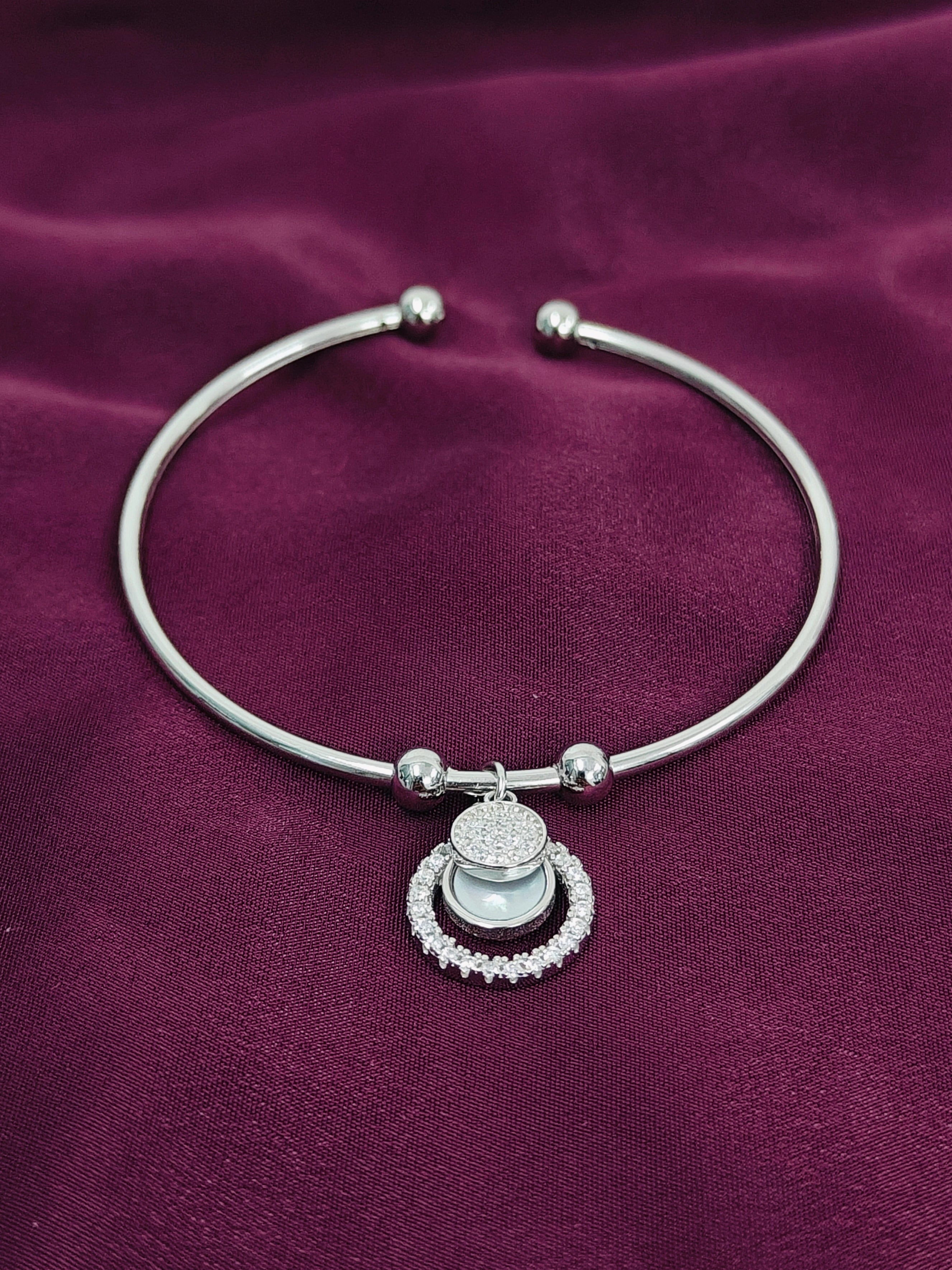 Silver bracelet with a charm on a purple fabric background