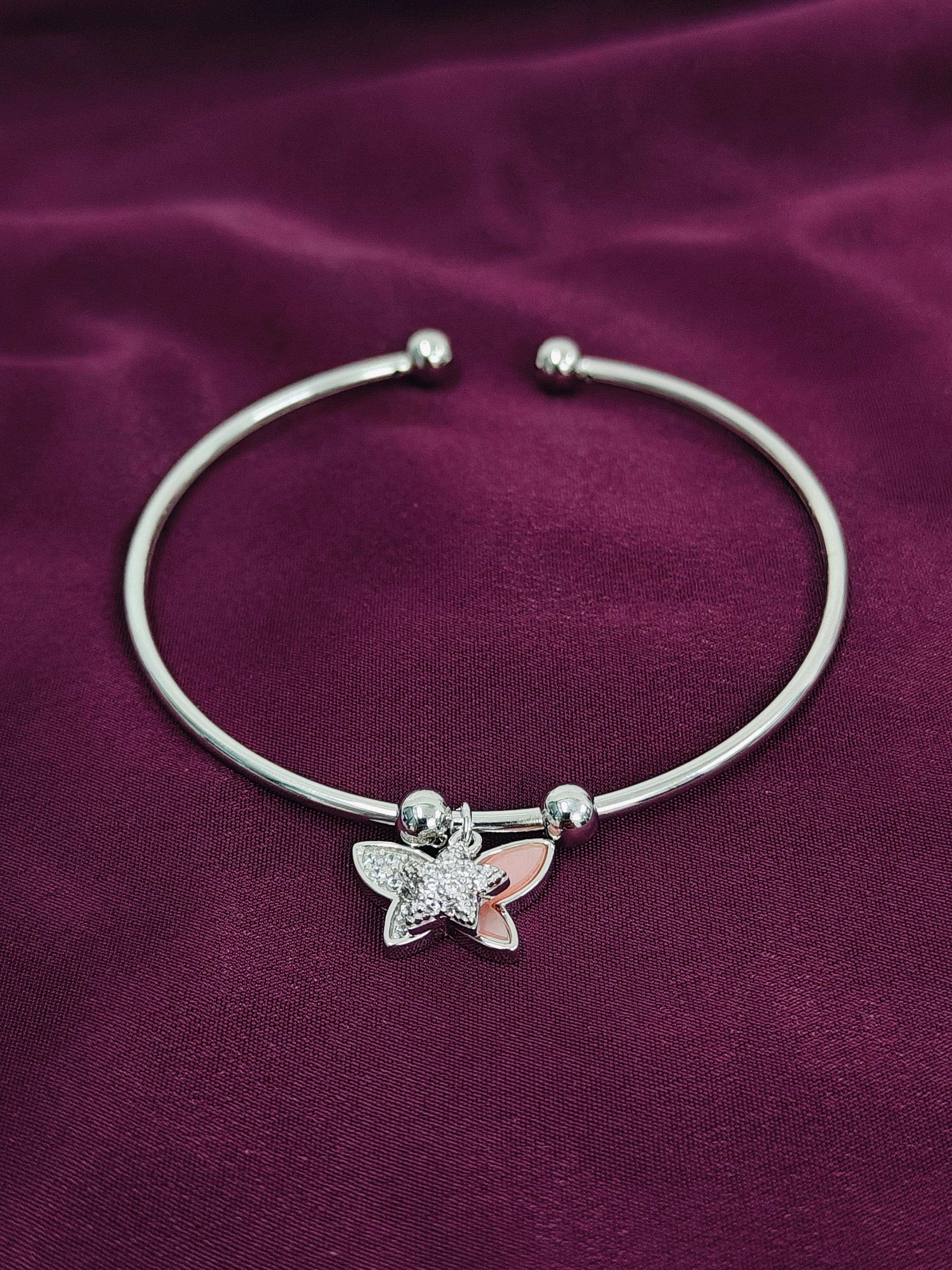 Silver bracelet with a butterfly charm on a purple fabric background