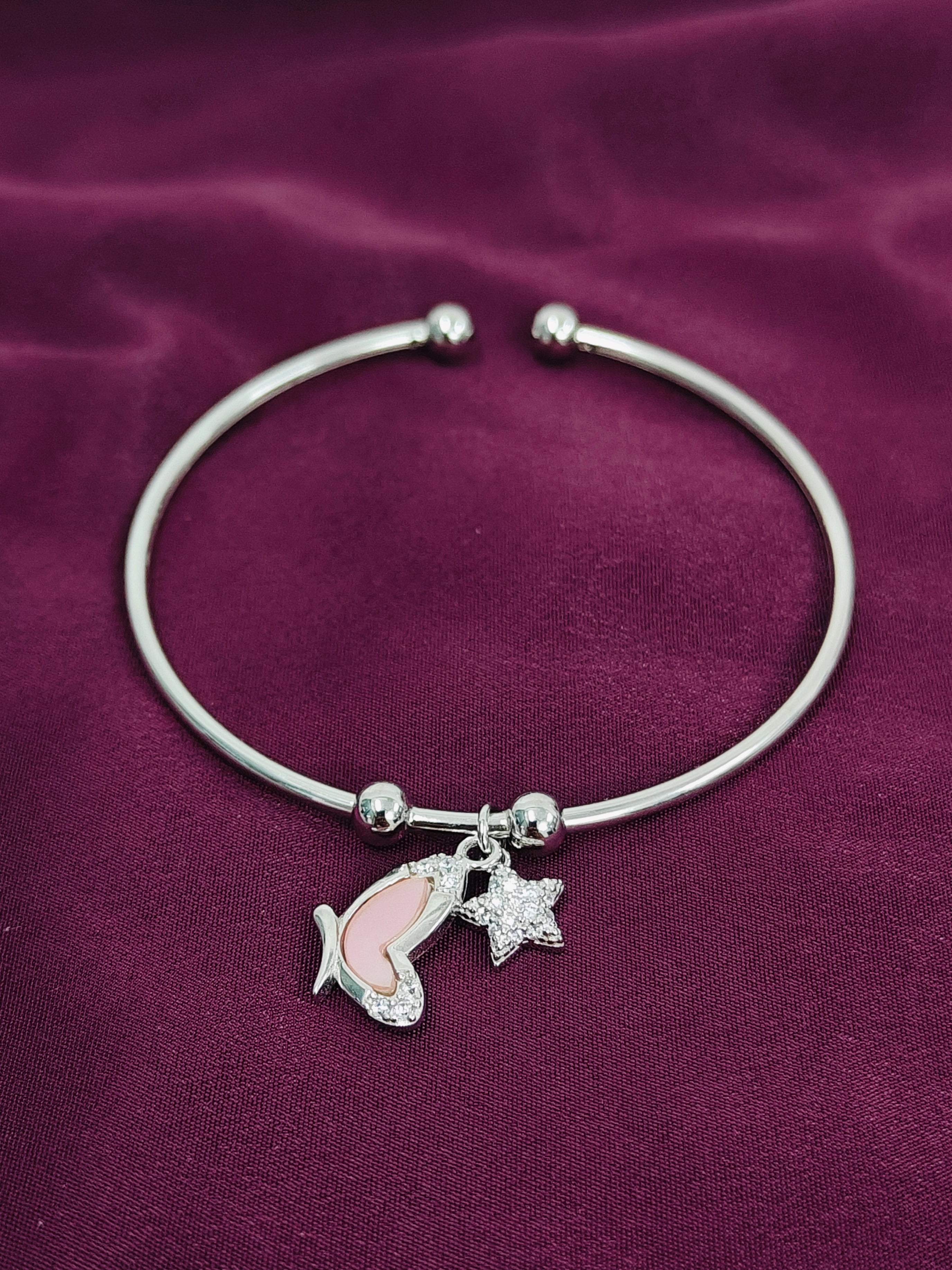 Silver bracelet with a dolphin and starfish charm on a purple fabric background
