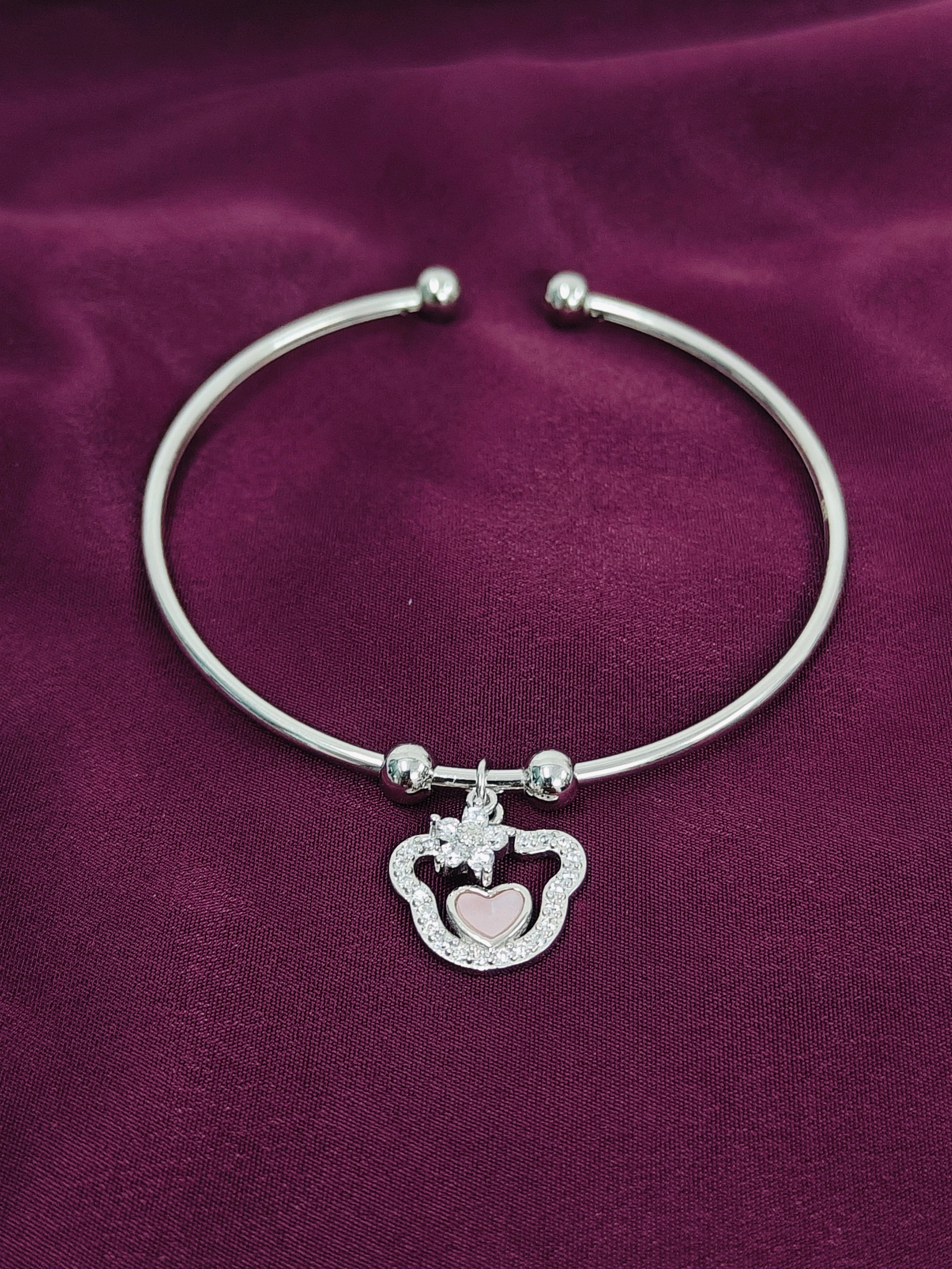 Silver bracelet with a heart-shaped clasp on a purple fabric background