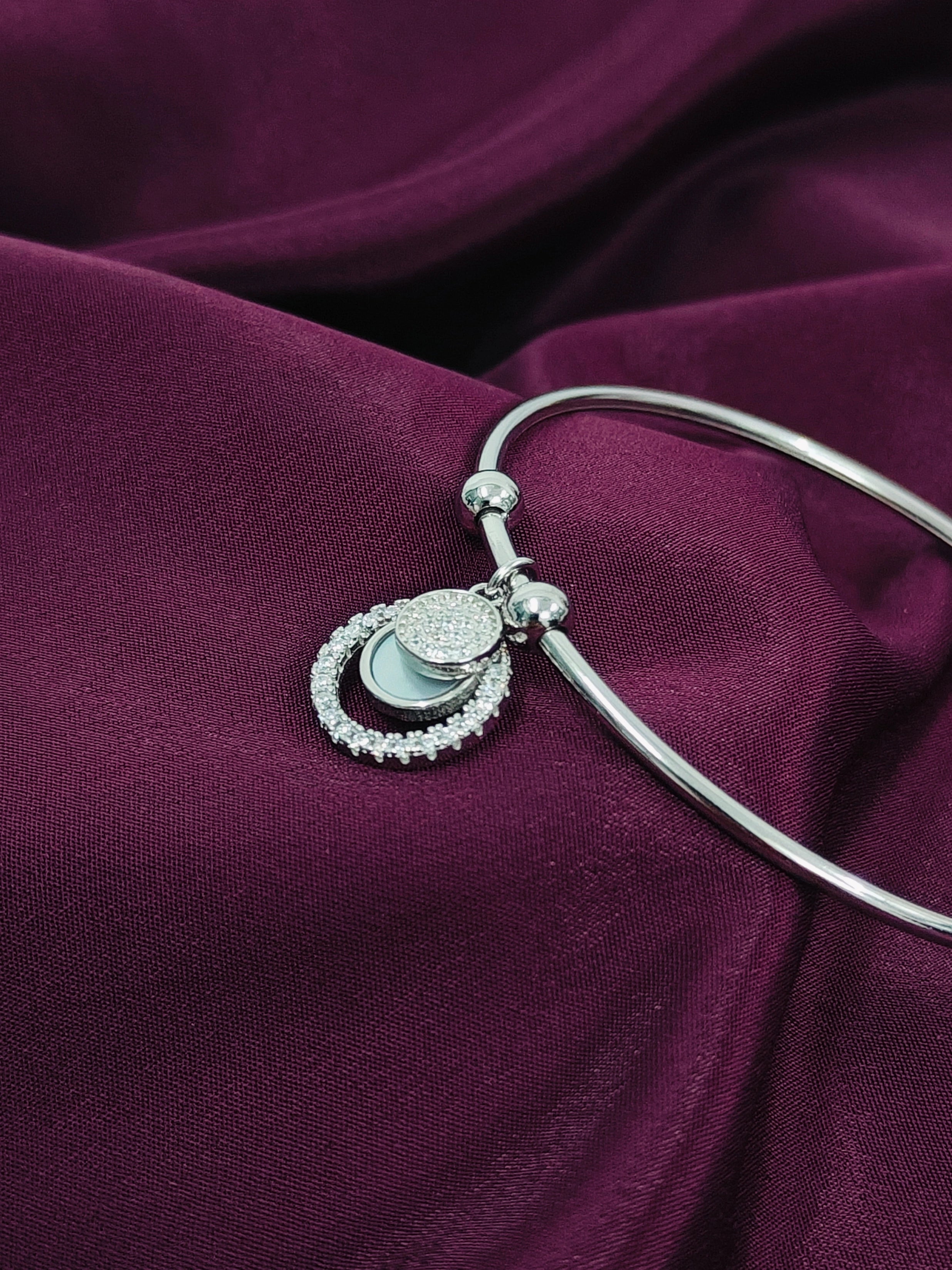 Silver bracelet with a detailed pendant on a purple fabric background