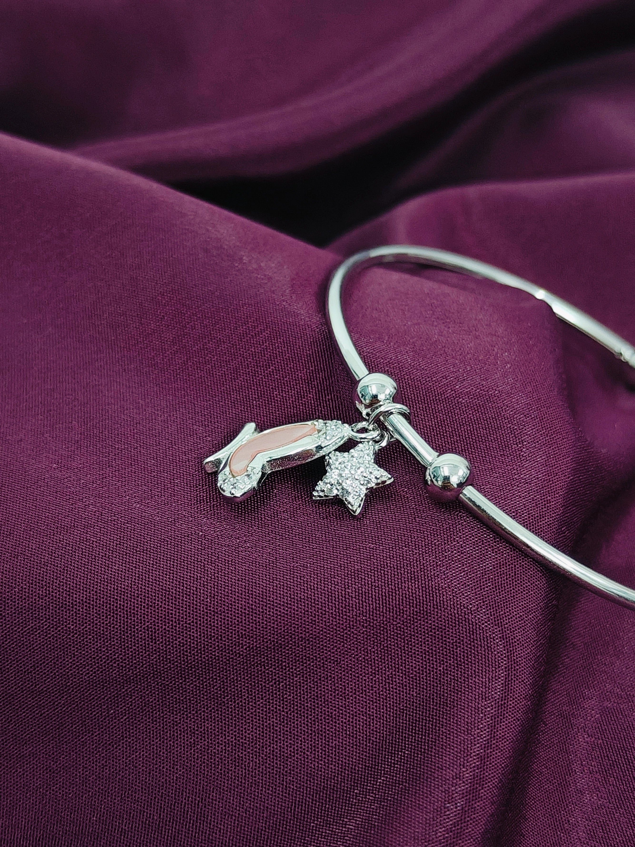 Silver bracelet with charms on a purple fabric background